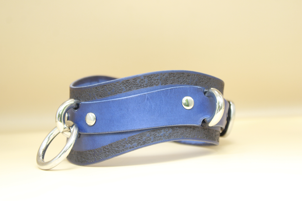 A blue leather choker necklace with metal rings and a metal clasp.