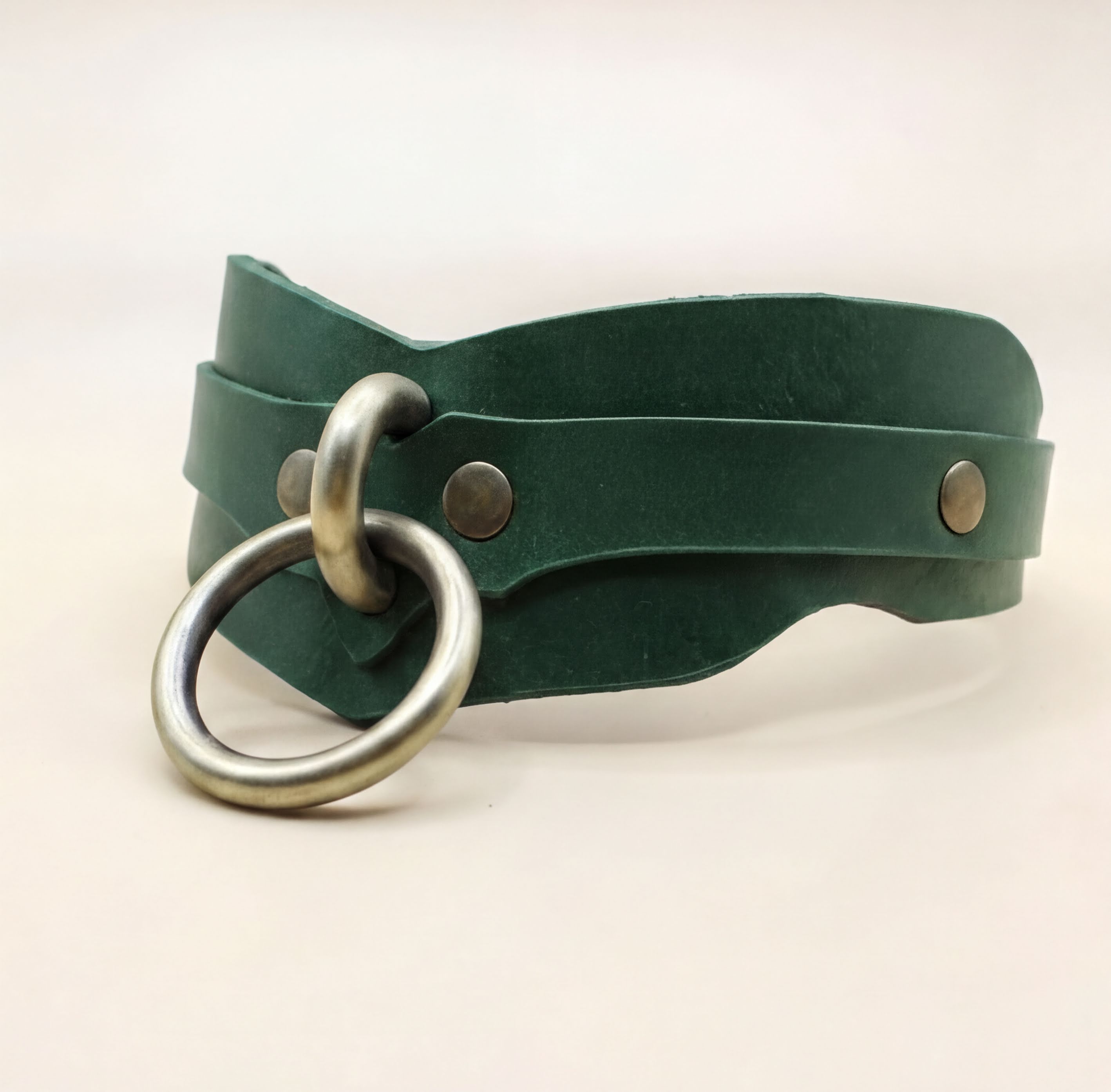 A green leather choker necklace with a metal ring and two metal fasteners.