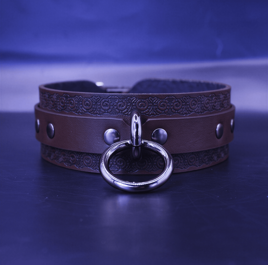 A brown leather choker necklace with a metal ring and buckle, set against a dark blue background.