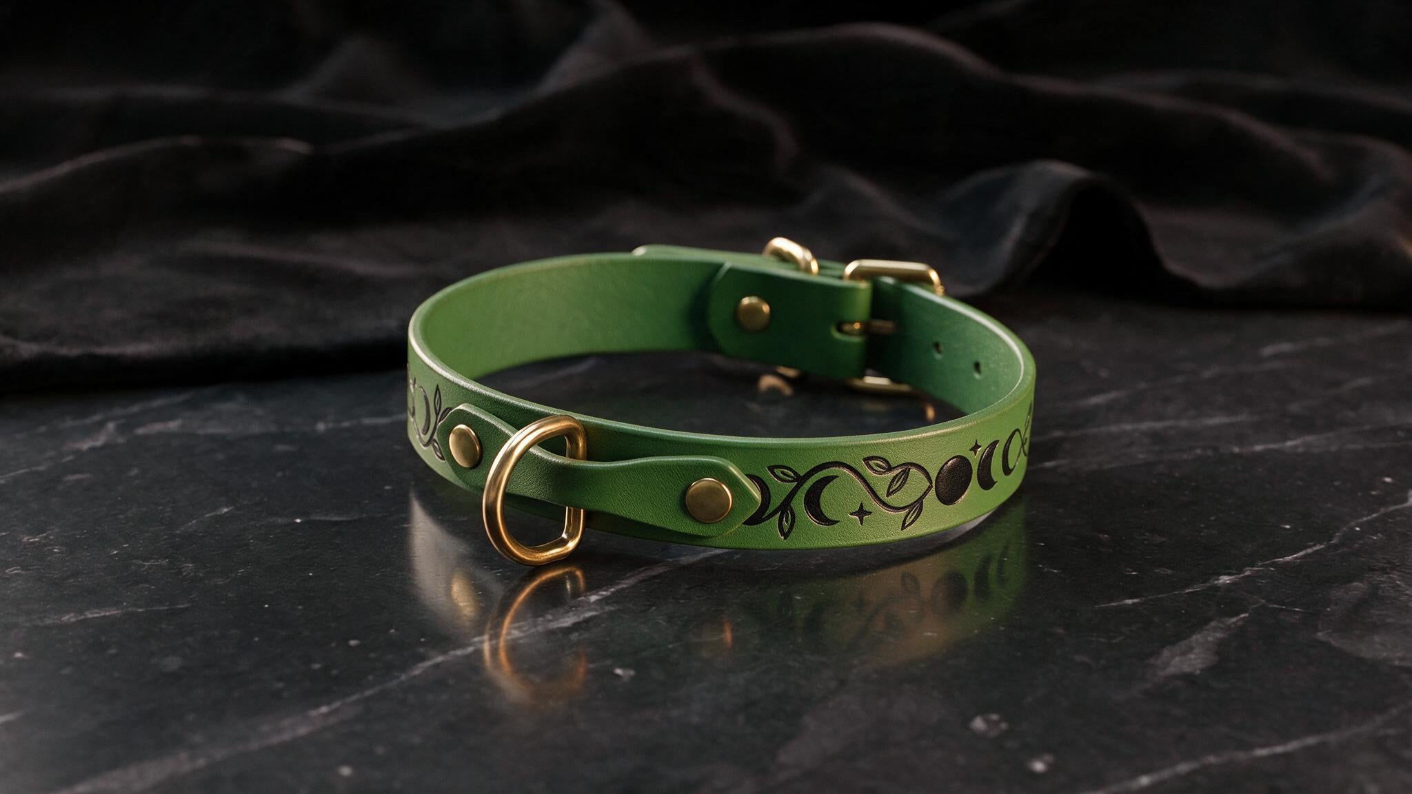A green leather collar with a decorative pattern on it, placed on a black marble surface.