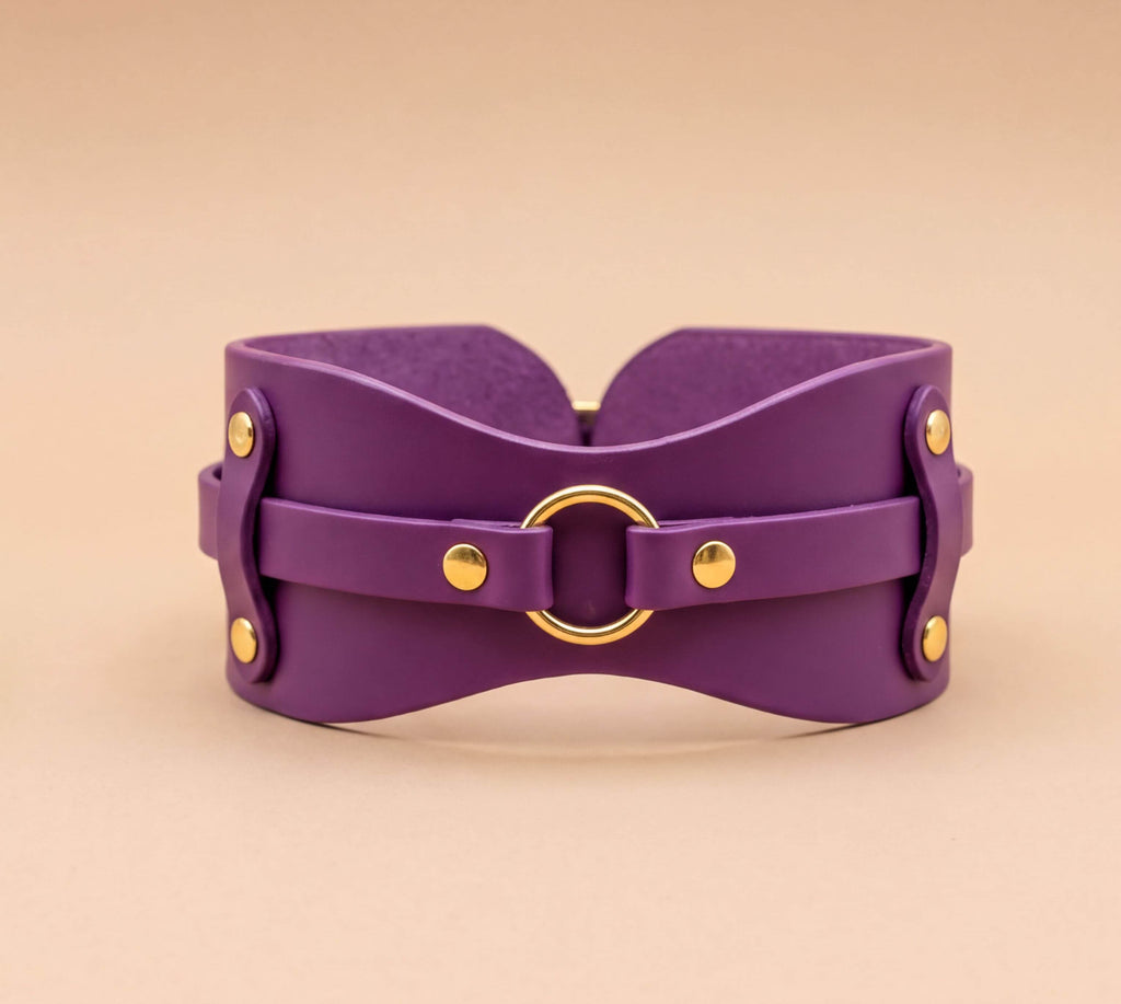 A purple leather corset with a gold ring and metal fasteners.