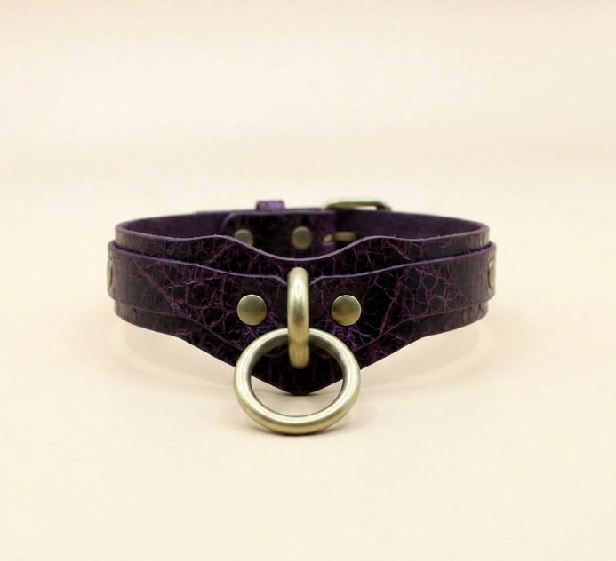 A purple leather choker collar with a gold ring and buckle.