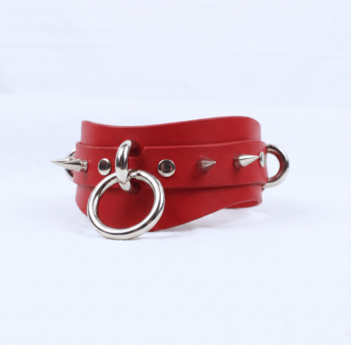 A red leather choker necklace with metal spikes protruding from it.