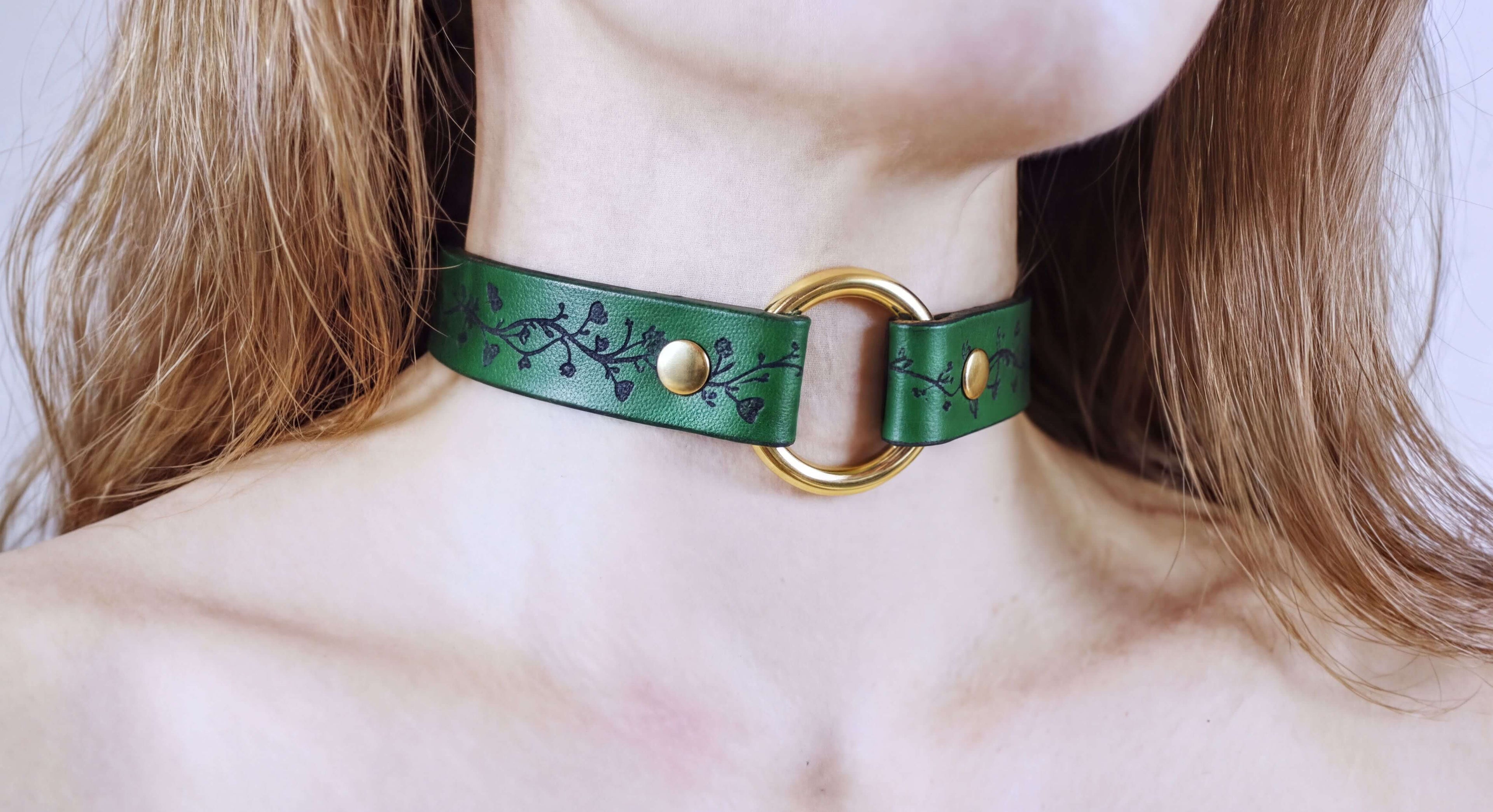 A close-up of a woman's neck wearing a green choker necklace with a gold ring.