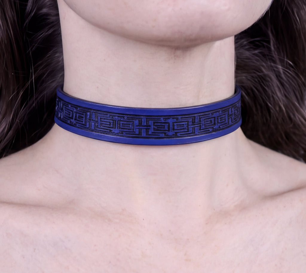 A close-up view of a person's neck and chest area wearing a blue choker necklace with a black geometric pattern.