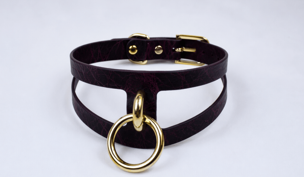 A dark purple choker necklace with a gold-colored metal ring and buckle.