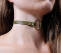 A close-up view of a person's neck and chin area, featuring a green leather choker necklace with a gold-colored circular clasp.