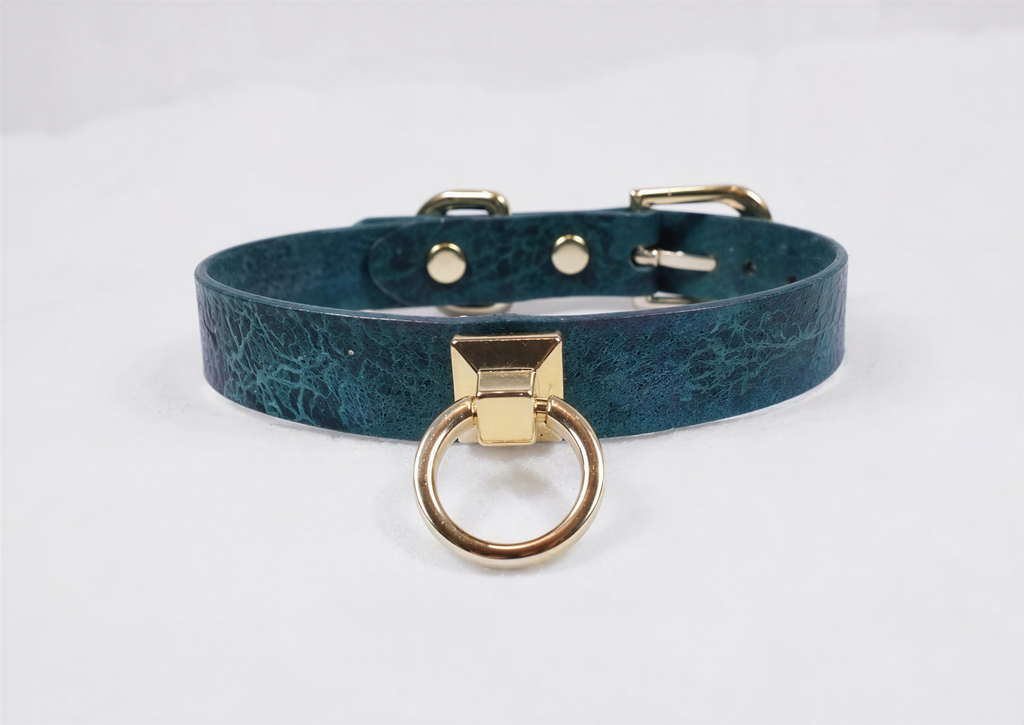 A teal-colored leather choker collar with a gold-colored metal ring and buckle.