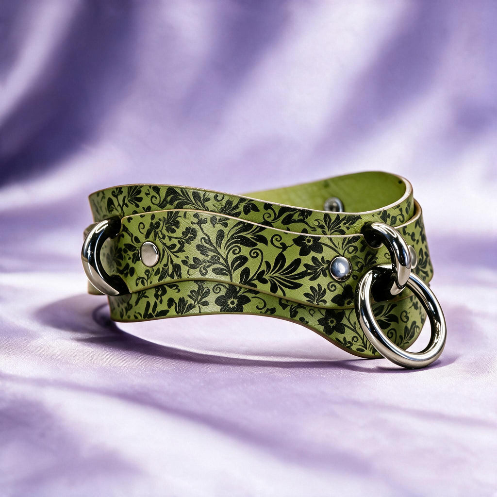 A green leather belt with a floral pattern and metal rings is displayed against a purple background.