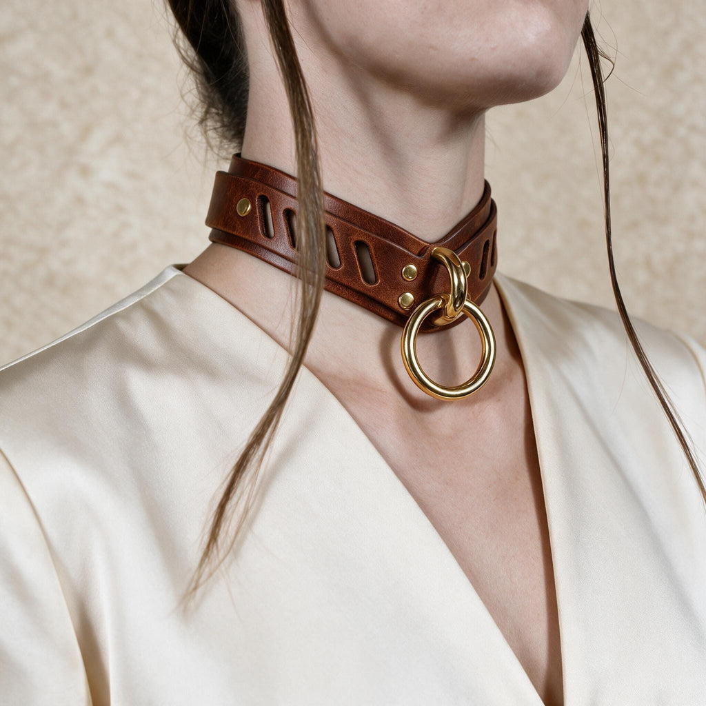 A close-up of a woman wearing a brown leather choker necklace with a gold ring.