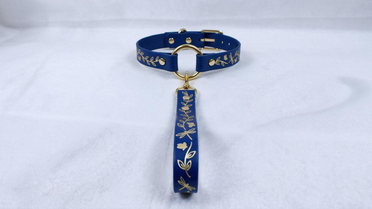 A blue collar with gold leaf designs and a gold-colored tag attached to it.