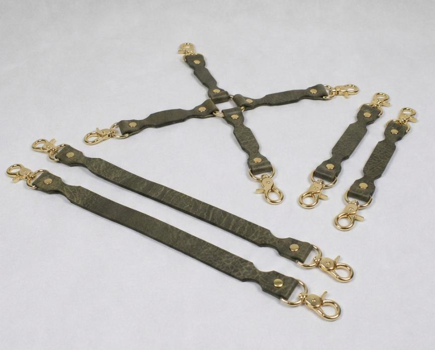 a collection of leather straps with gold-colored metal clasps, arranged in various orientations.