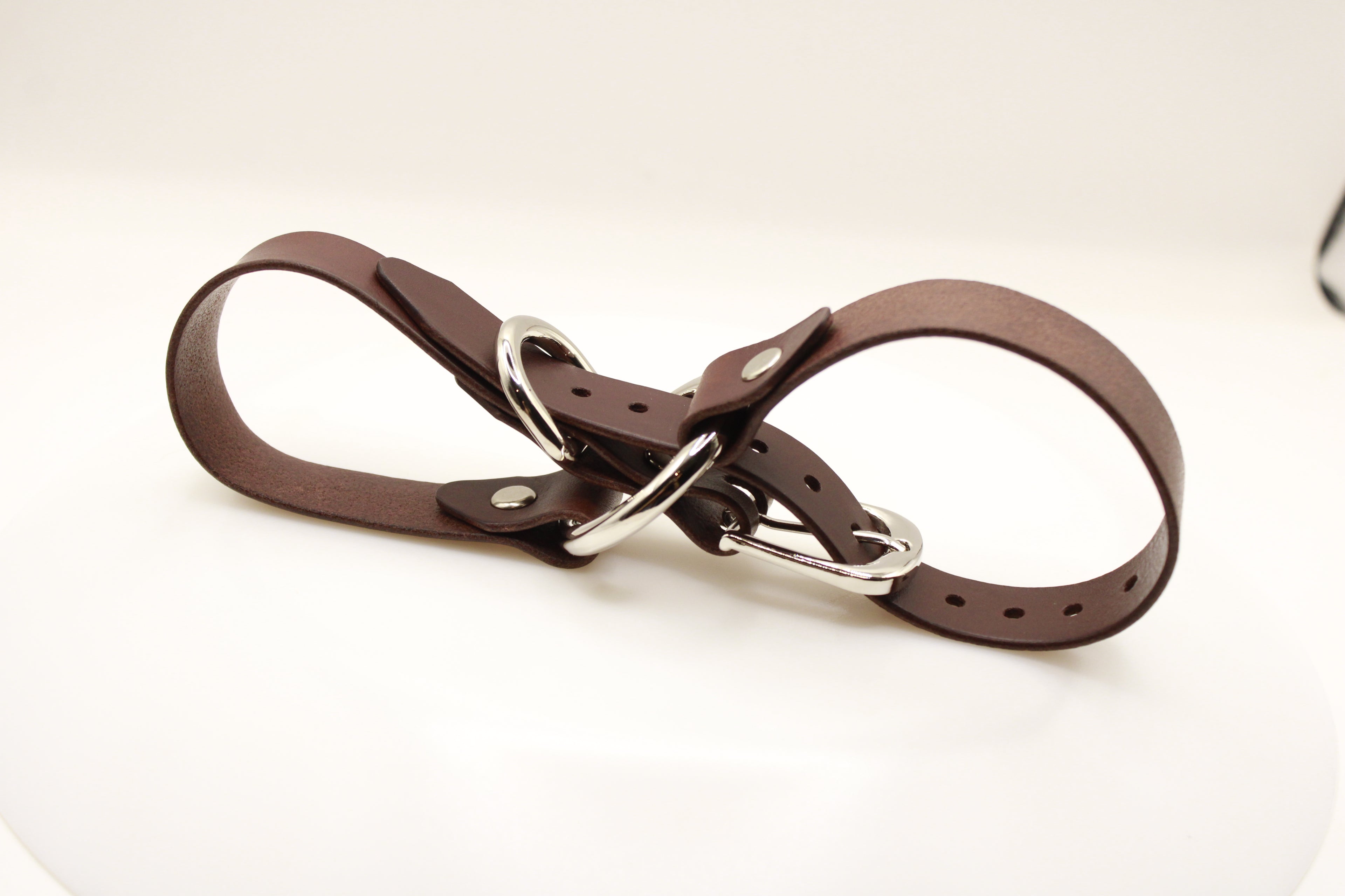 A brown leather belt with silver buckles and a metal clasp is shown in the image.