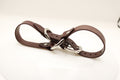 A brown leather belt with silver buckles and a metal clasp is shown in the image.