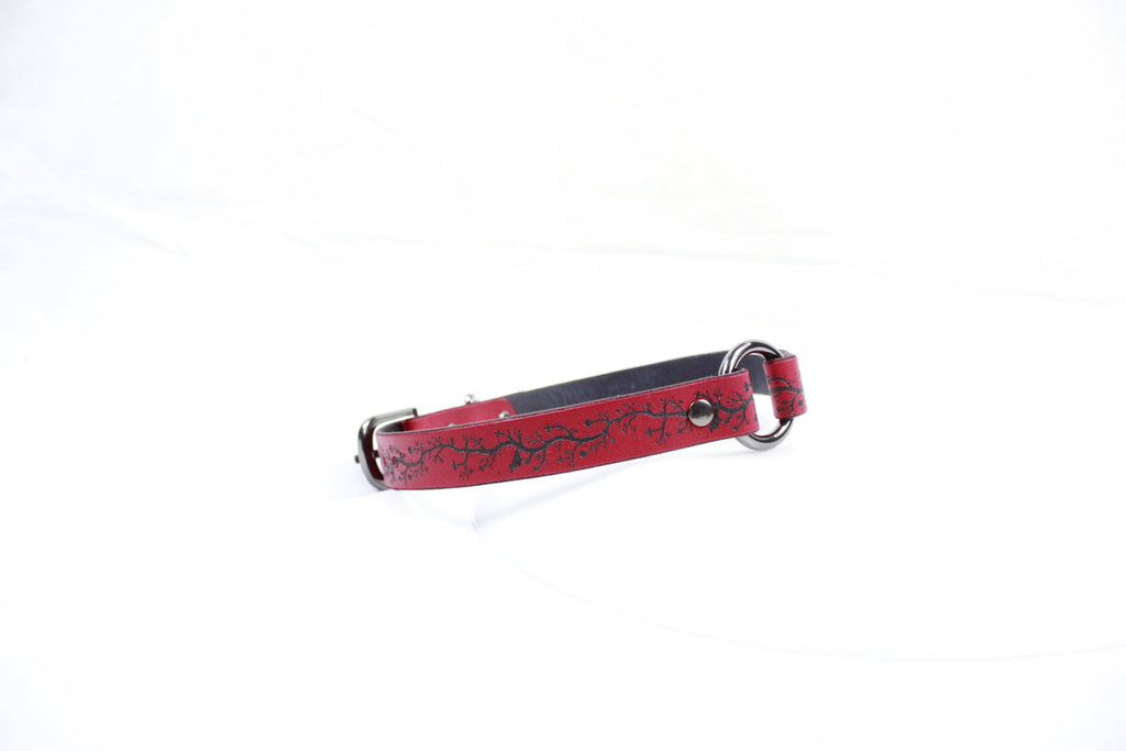 A red leather dog collar with a black floral pattern on it.
