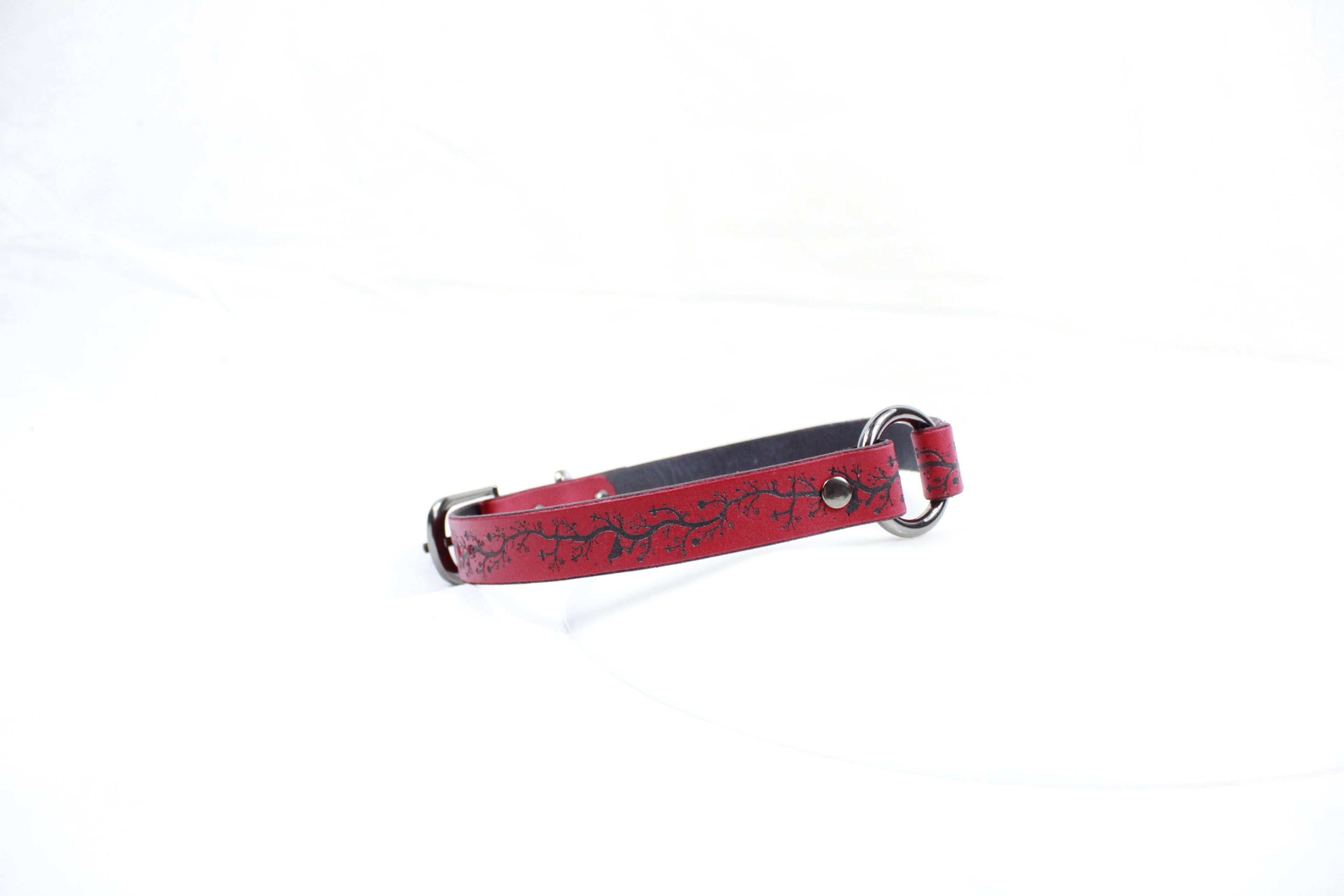 A red leather dog collar with a black floral pattern on it.