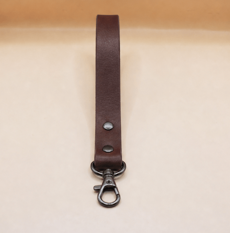 A brown leather strap with a metal clasp and hook attached to it.