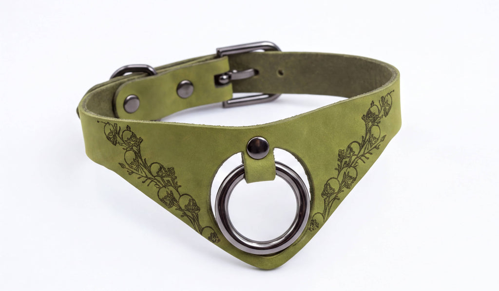 A green leather choker necklace with a metal ring and a floral design on the front.