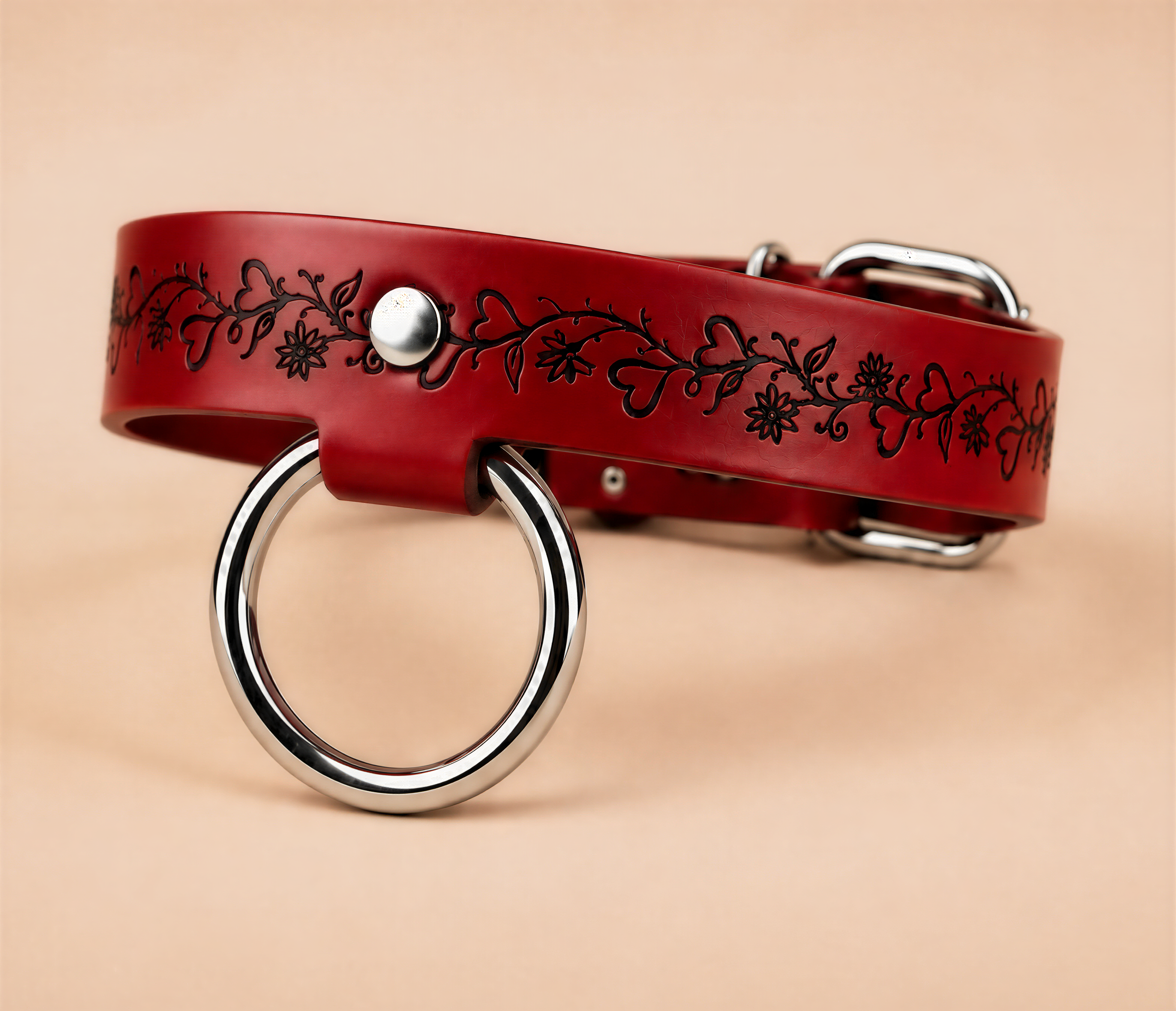 A red leather collar with a silver ring and floral design on it.