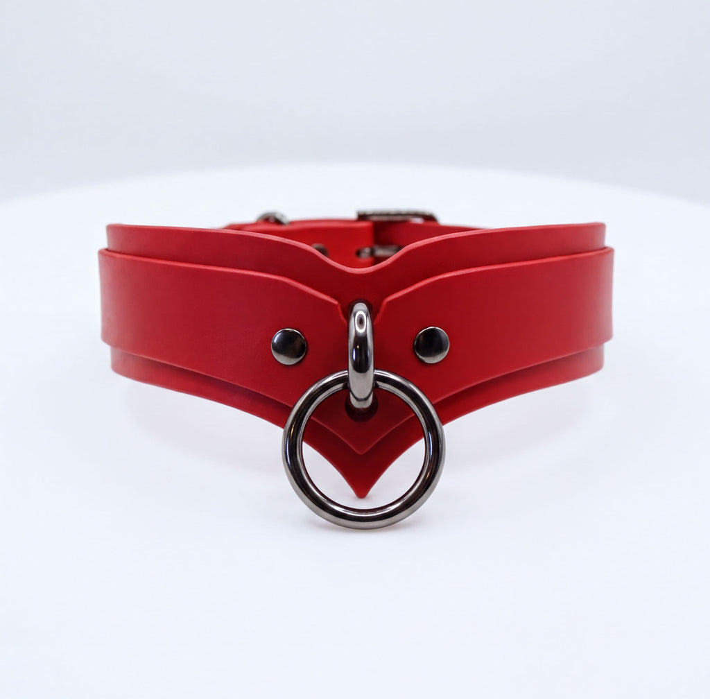 A red leather choker collar with a metal ring and buckle.