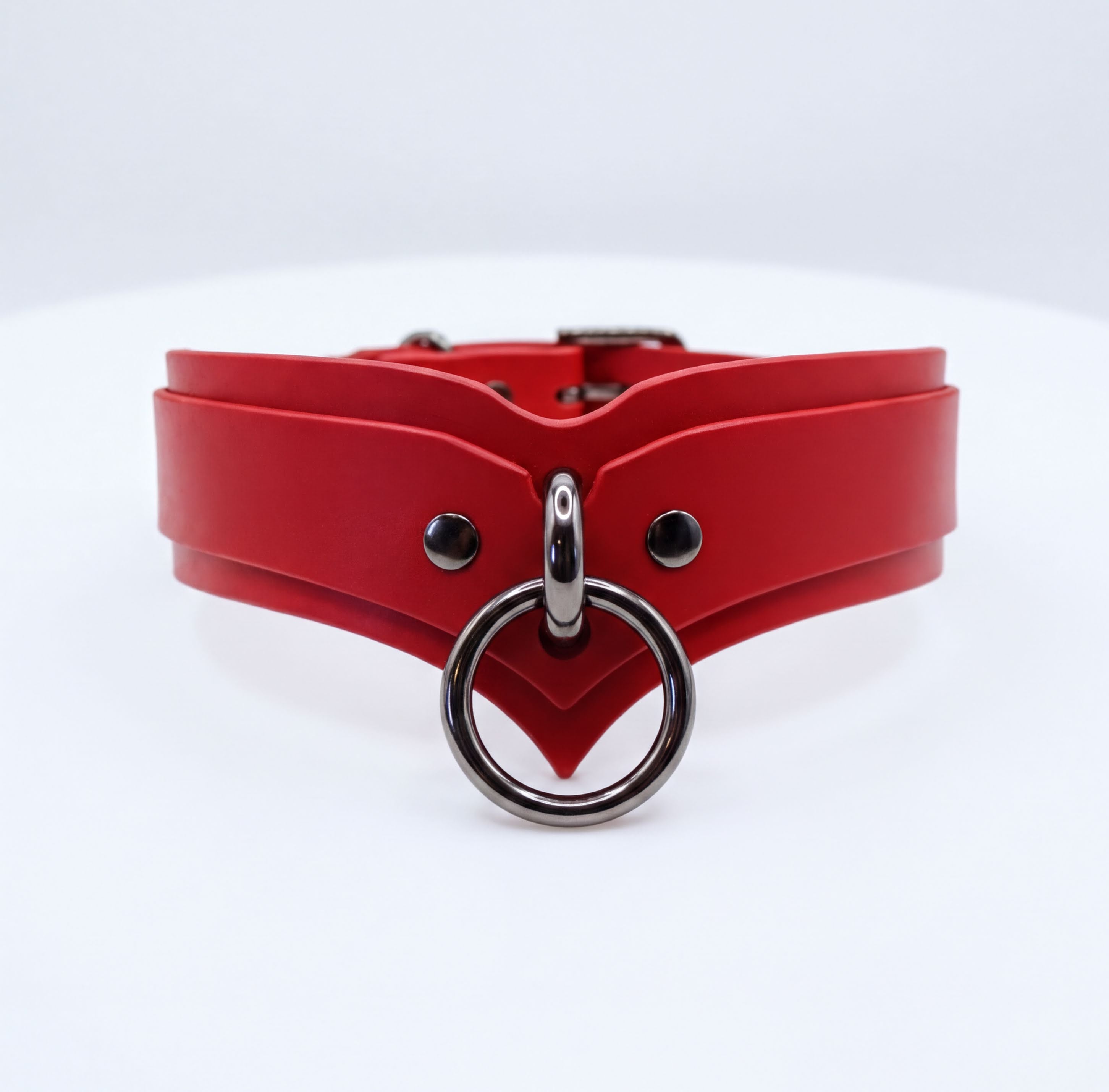 A red leather choker collar with a metal ring and buckle.