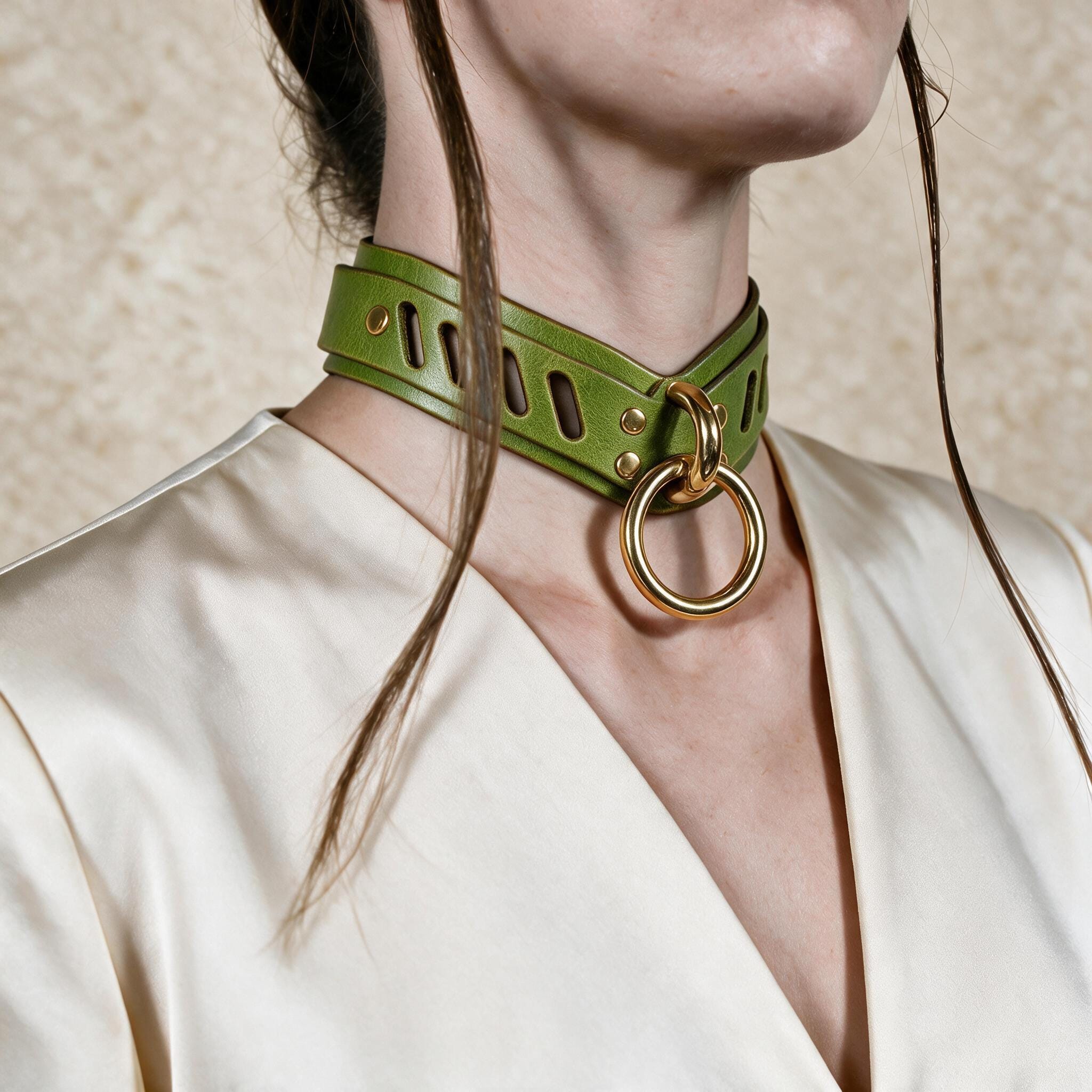 A close-up of a person wearing a green leather choker necklace with a gold ring.