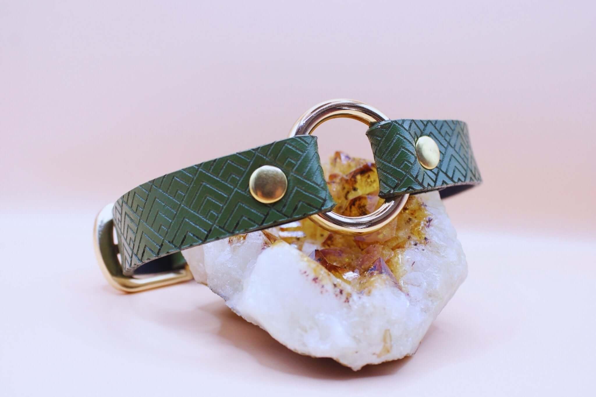 Green leather geometric O-ring submissive collar on crystal, ideal for BDSM fashion and play.