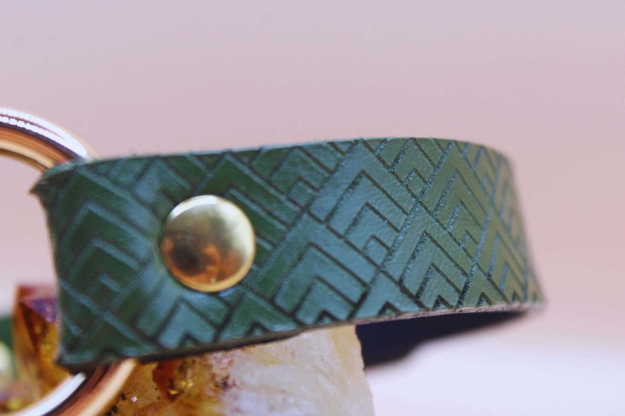 Close-up of geometric embossed deep forest green leather collar, showcasing BDSM design and subtle elegance for submissive fashion.