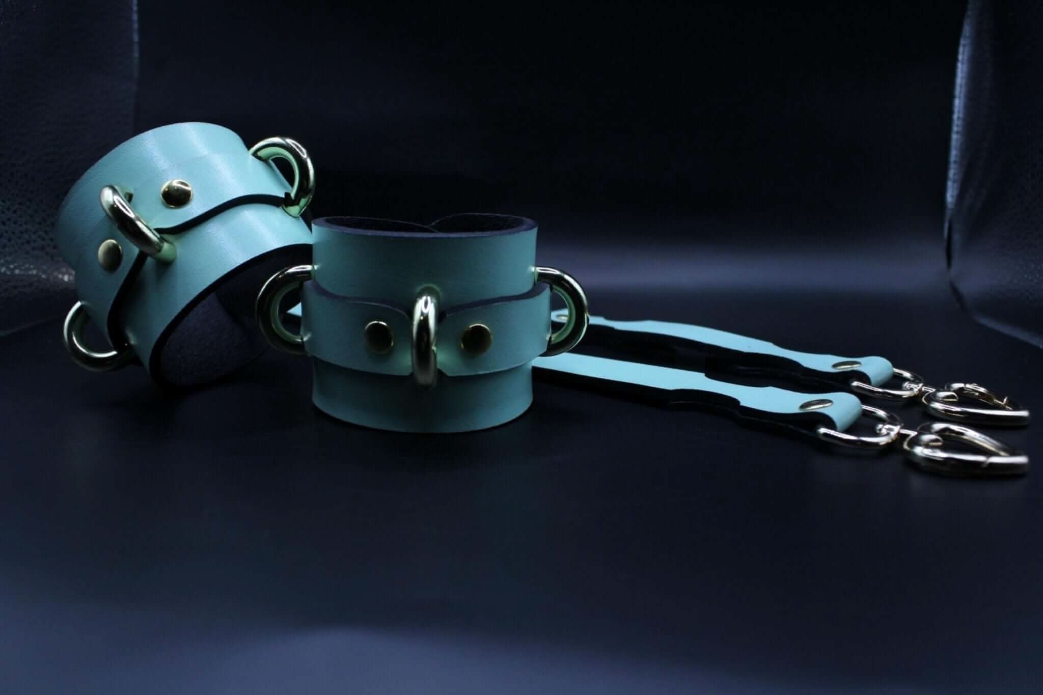 Handmade leather cuffs in teal, adjustable wrist or ankle restraints with connectors for BDSM play.