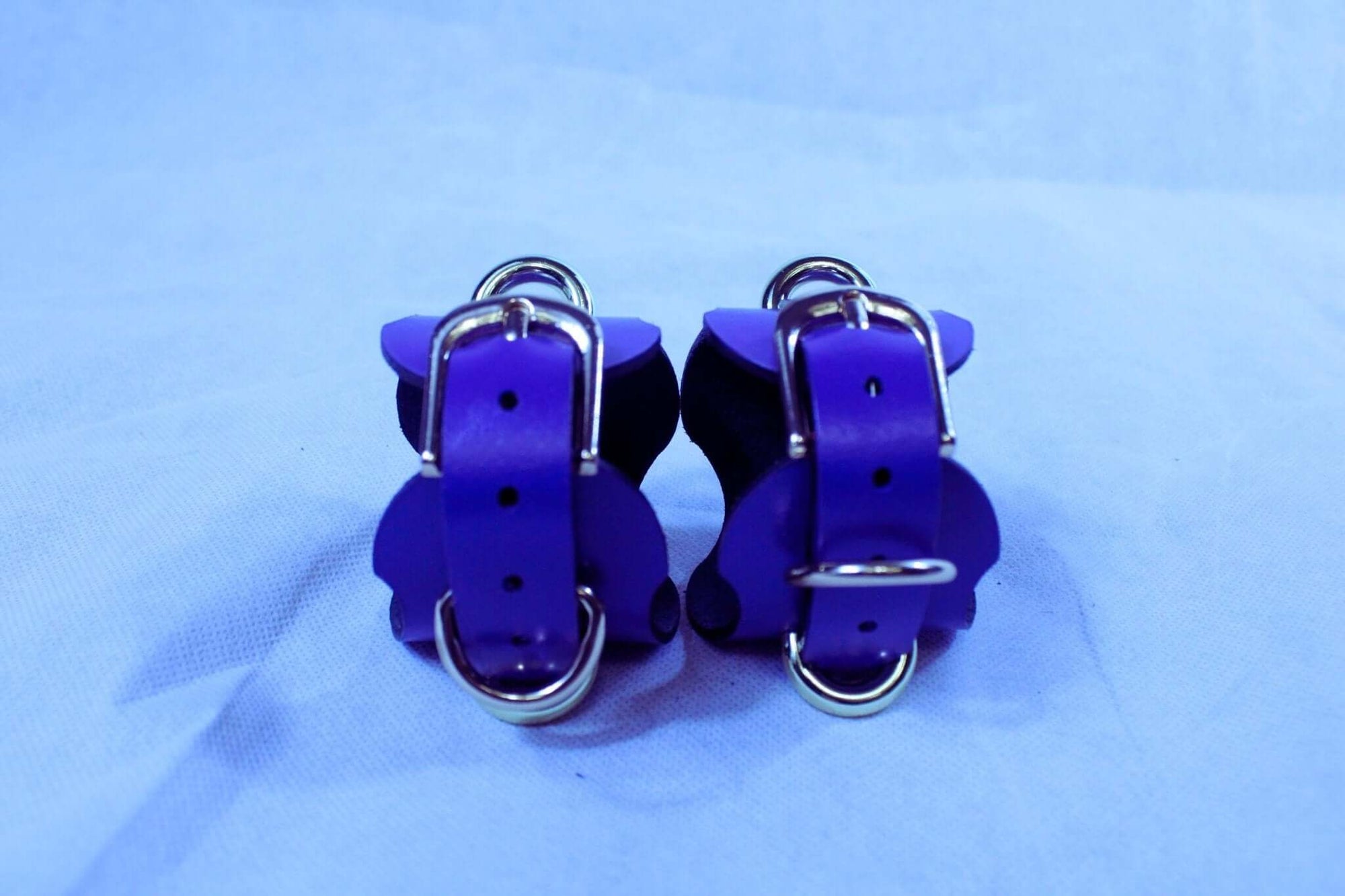 Handmade purple leather wrist cuffs with metal connectors, perfect for BDSM restraint and submissive play.