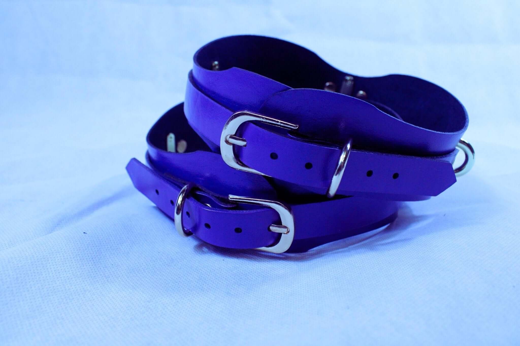 Handmade purple thigh cuffs made of genuine leather, ideal for bondage and BDSM play, featuring adjustable straps.