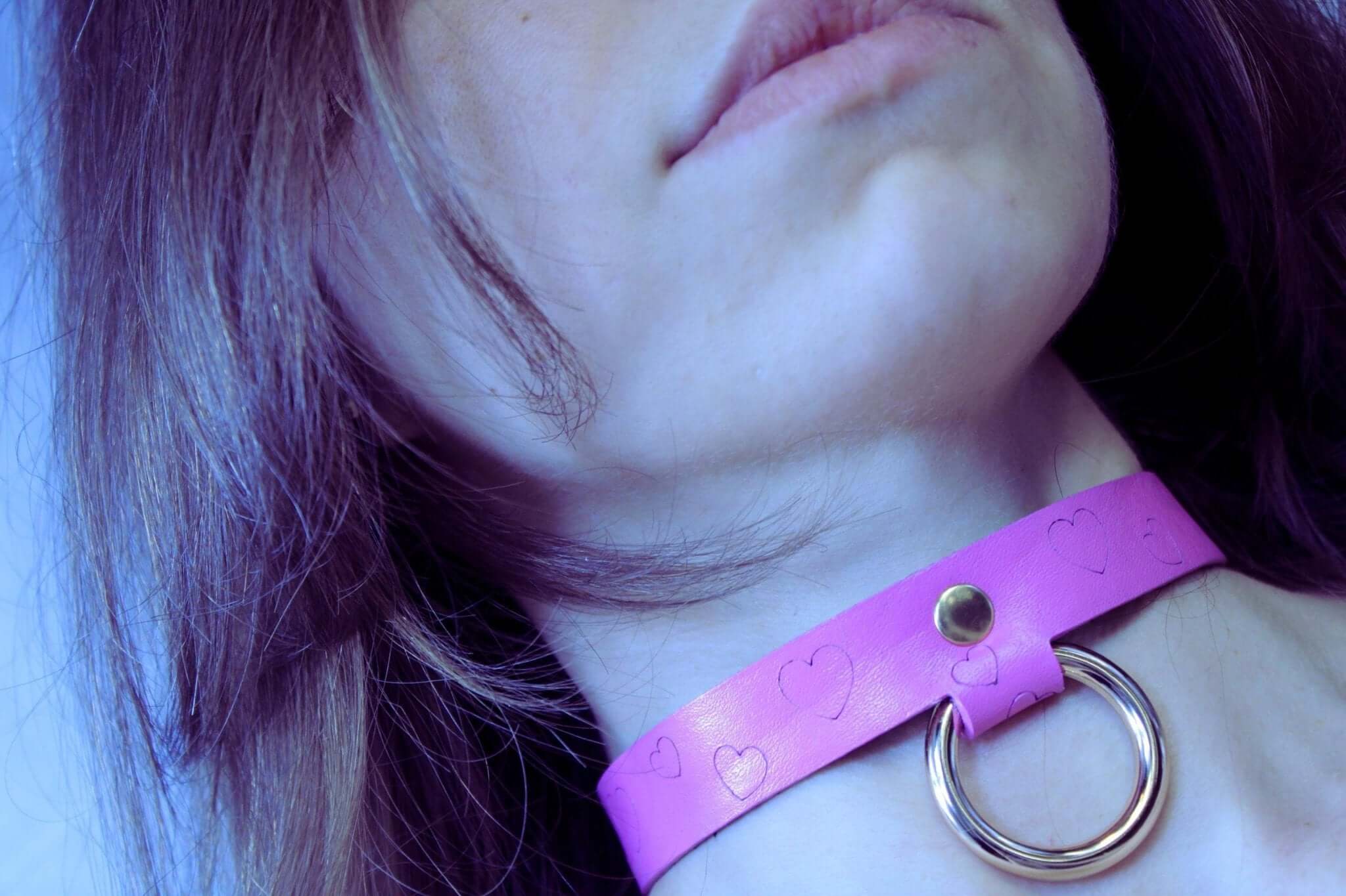 Heart print BDSM collar in pink leather with a metallic ring, perfect for submissive jewelry and bondage gear.