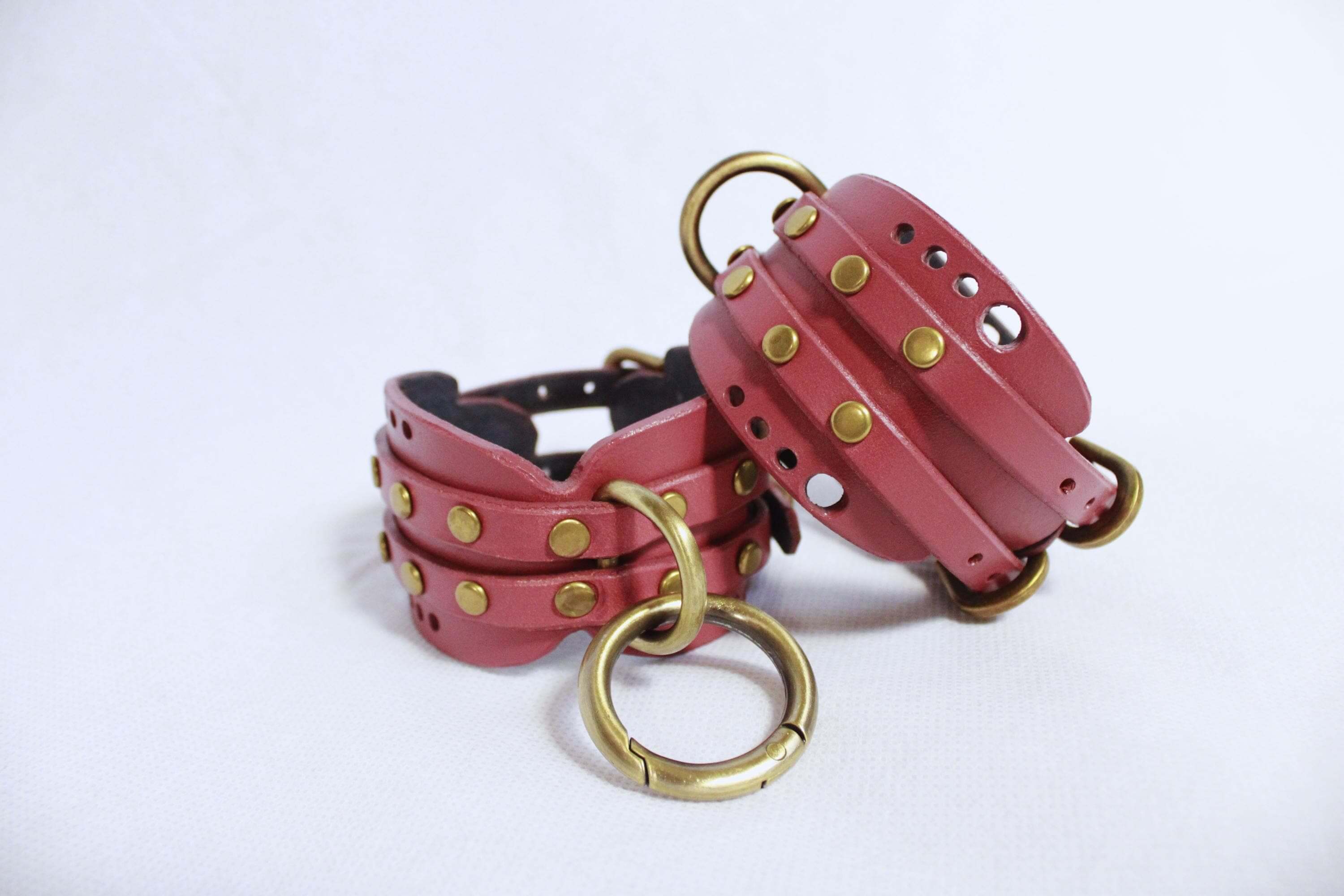 Handmade mauve leather wrist cuffs with brass hardware for BDSM and submissive play, versatile bondage gear.