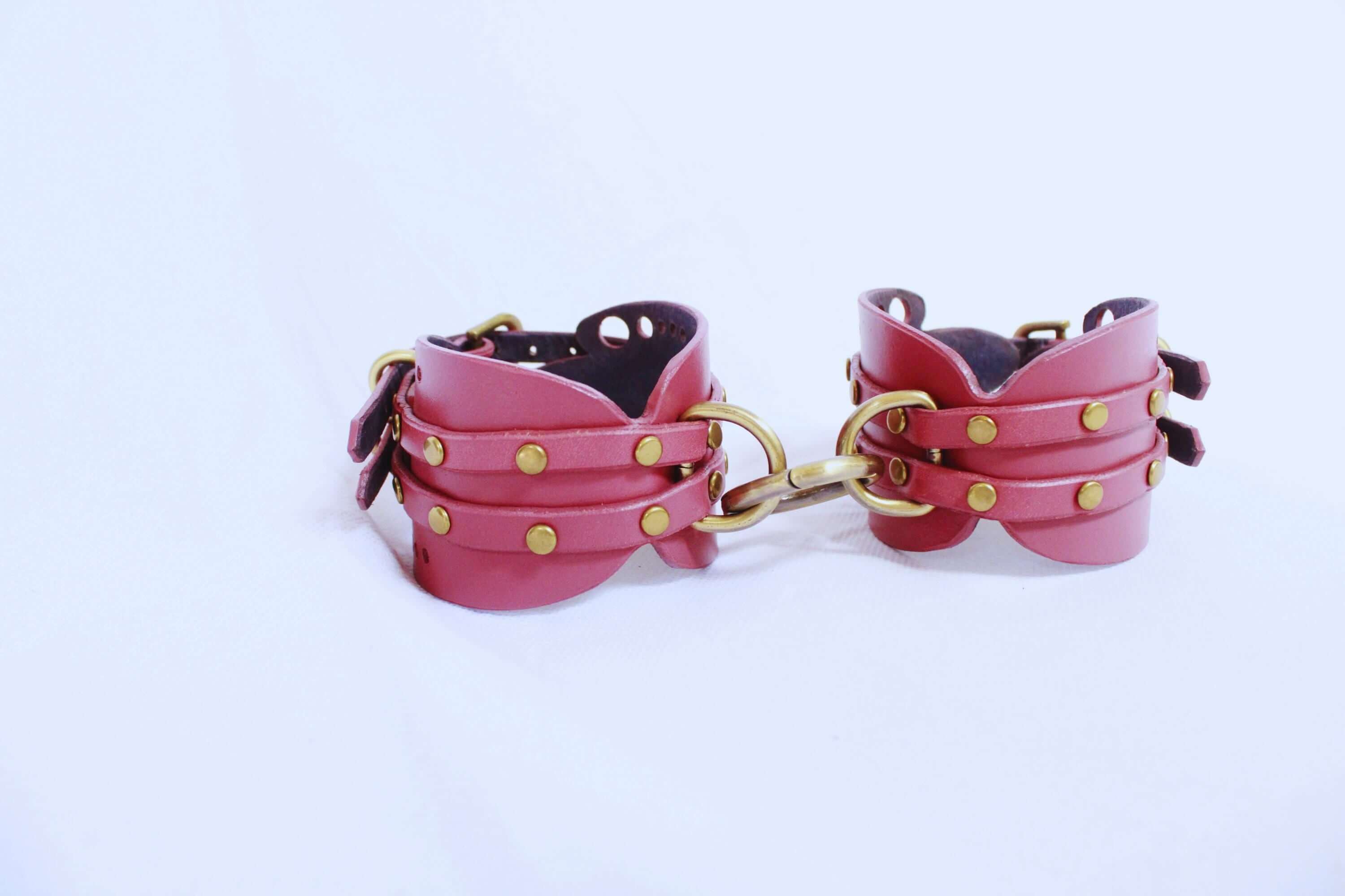 Handmade mauve leather wrist cuffs with brass hardware for BDSM bondage, perfect for submissive play and self-bondage.