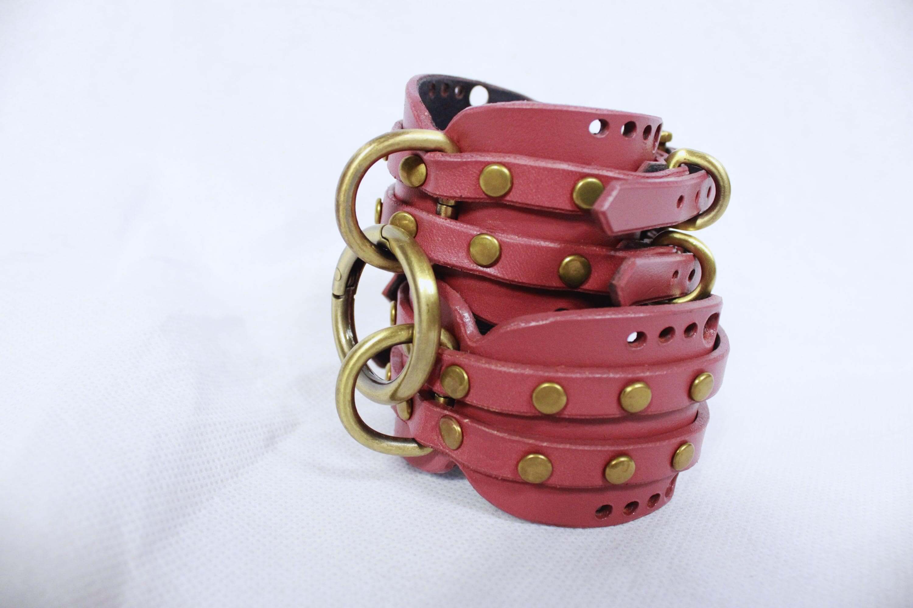 Handmade mauve leather wrist cuffs with brass hardware, perfect for BDSM bondage and submissive play.