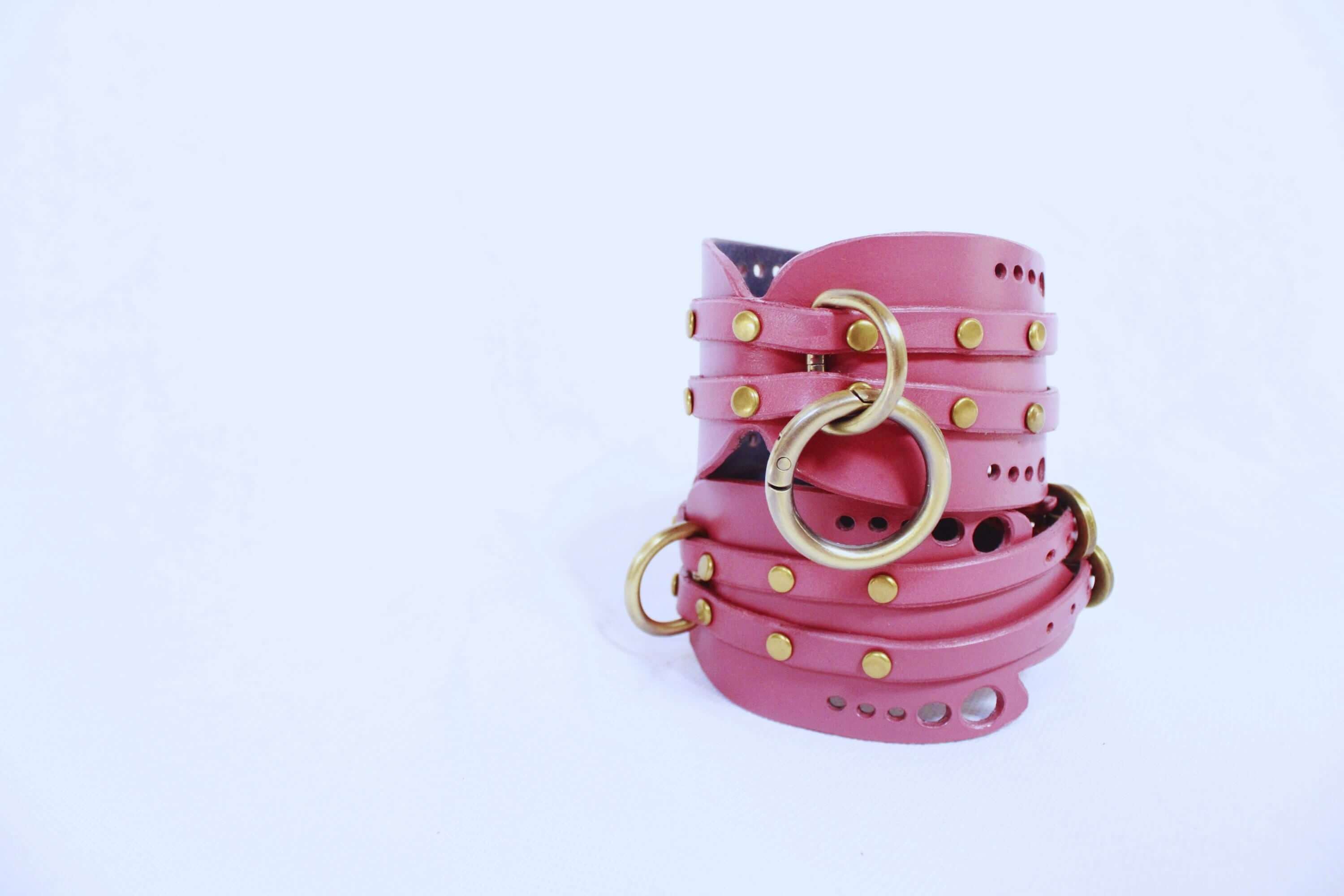 Handmade mauve leather wrist cuffs with brass hardware, perfect for BDSM play and submissive experiences.