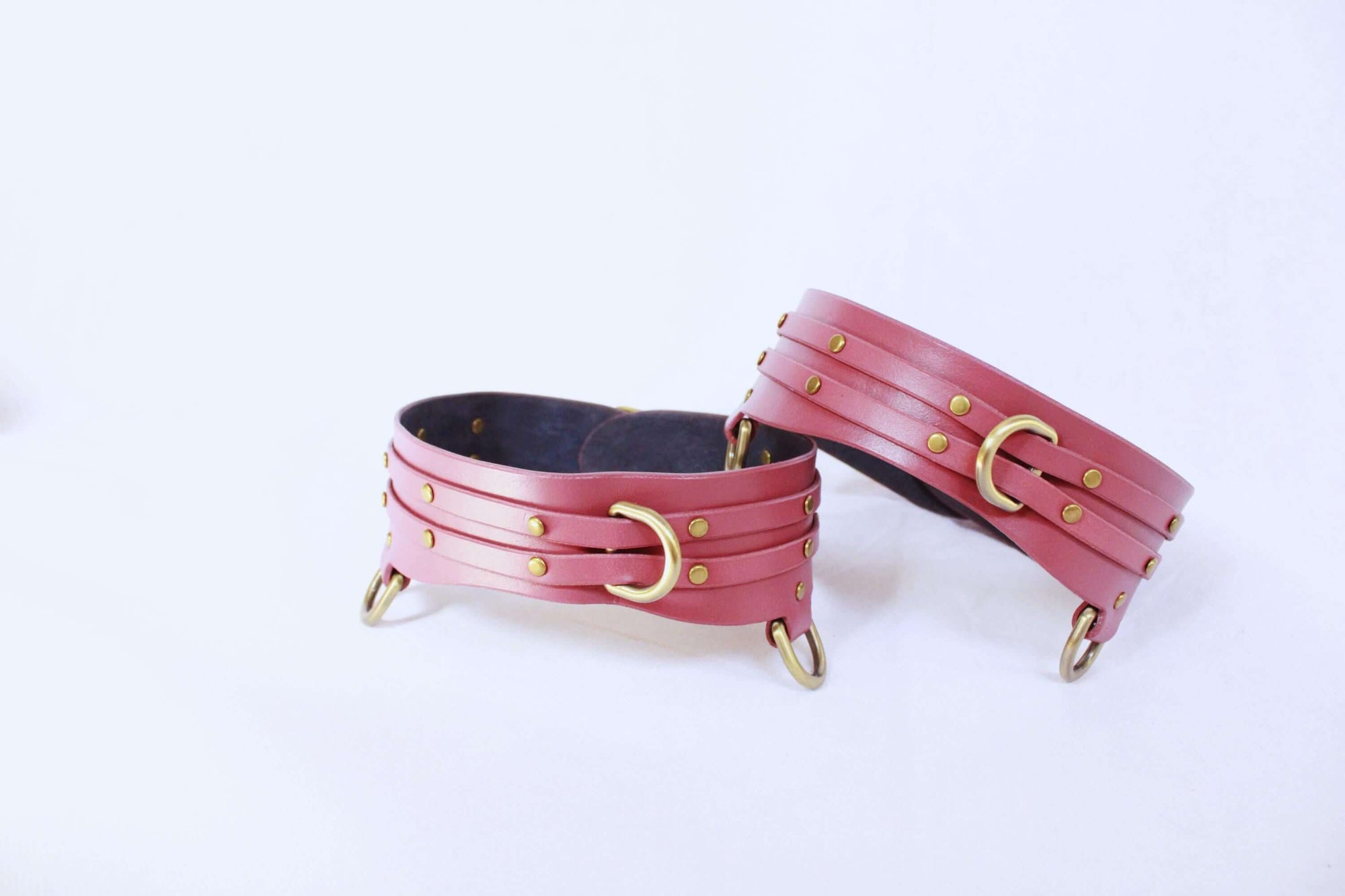 Adjustable leather thigh cuffs set with gold fittings, ideal for BDSM, bondage gear, and submissive accessories.