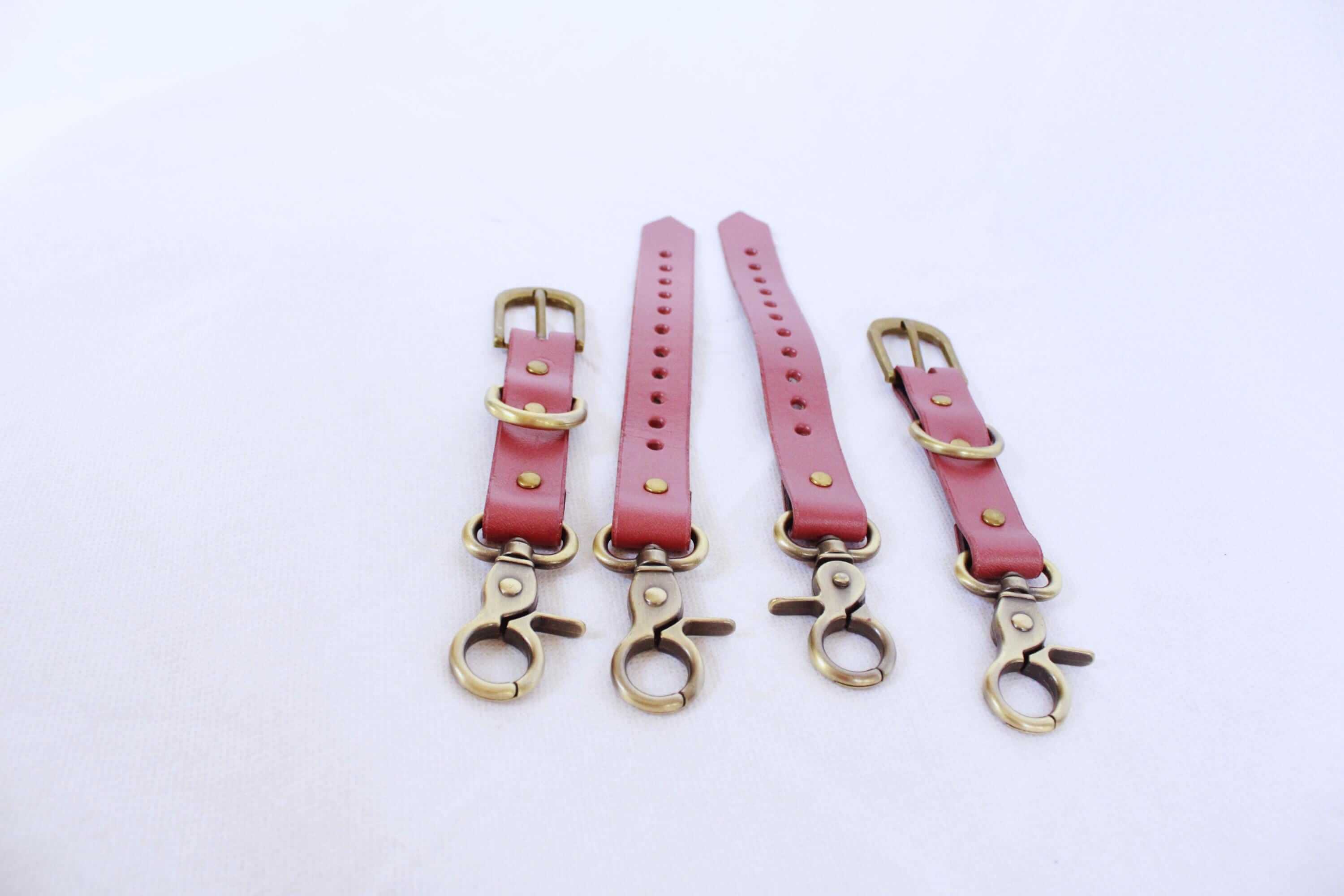 Adjustable pink leather thigh cuffs set with metal fittings for BDSM play, bondage gear for submissives.