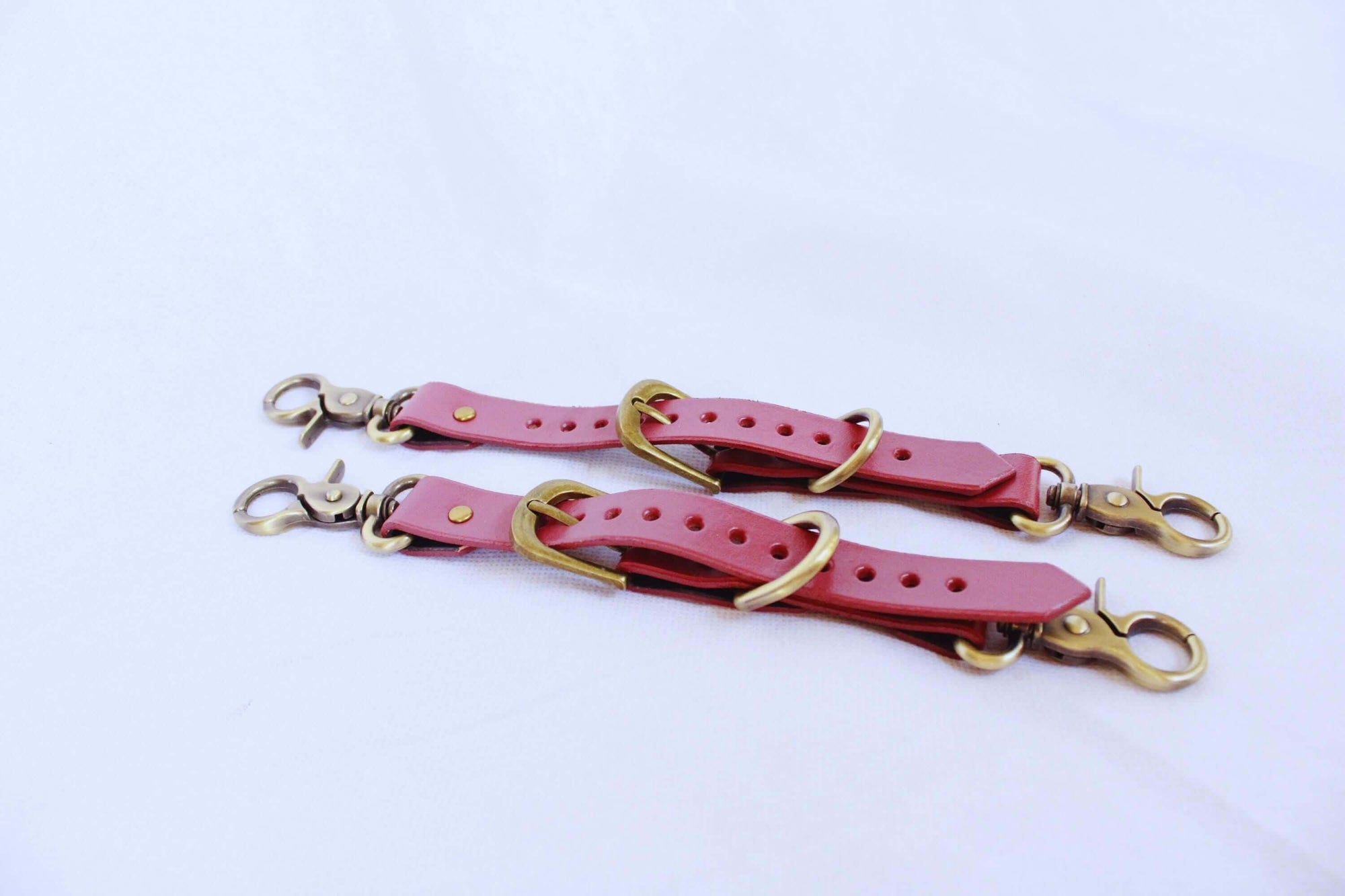 Adjustable leather thigh cuffs set designed for BDSM and bondage play, featuring durable metal fittings and vibrant color.