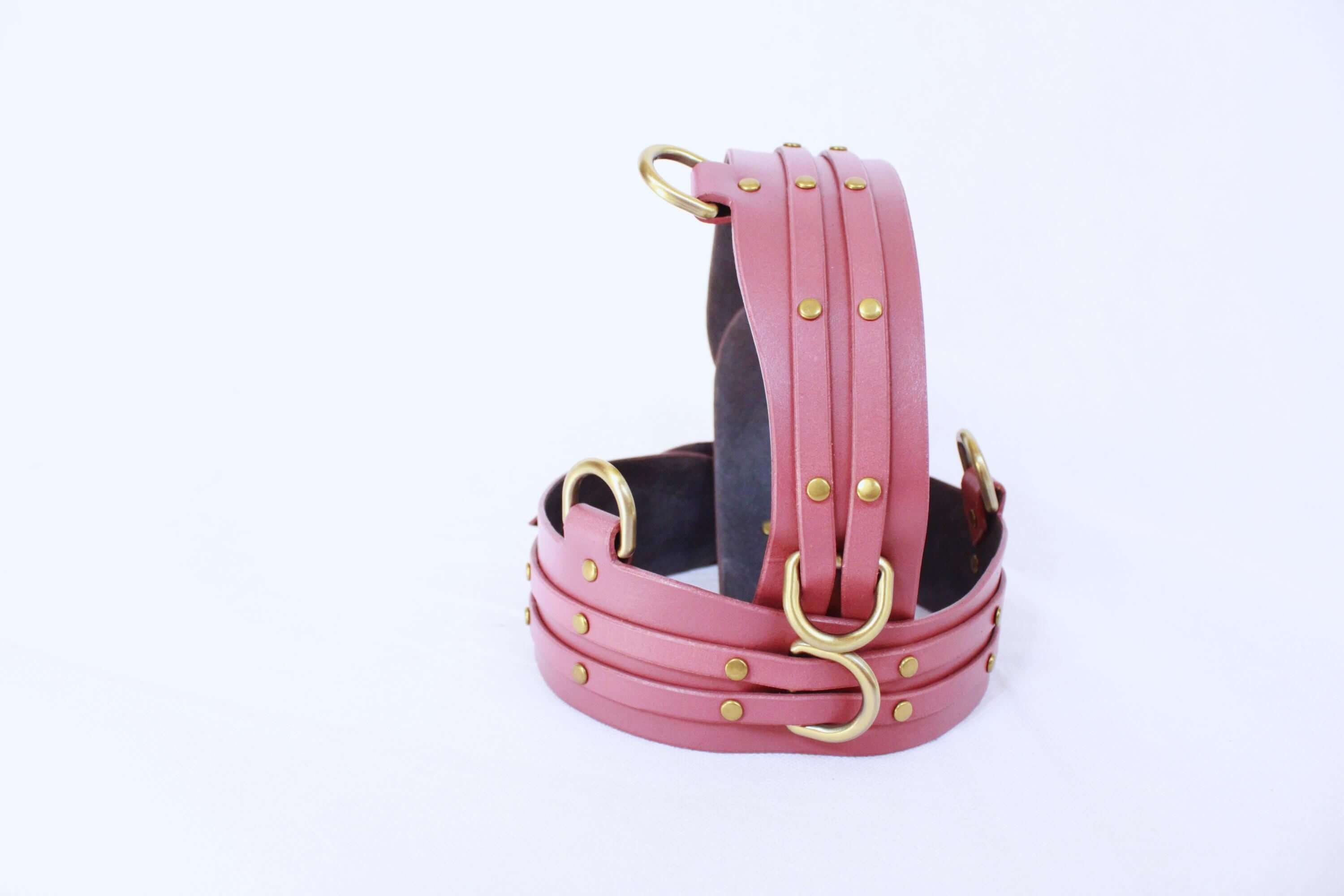 Adjustable pink leather thigh cuffs with metal fittings, perfect for BDSM bondage gear and submissive play.
