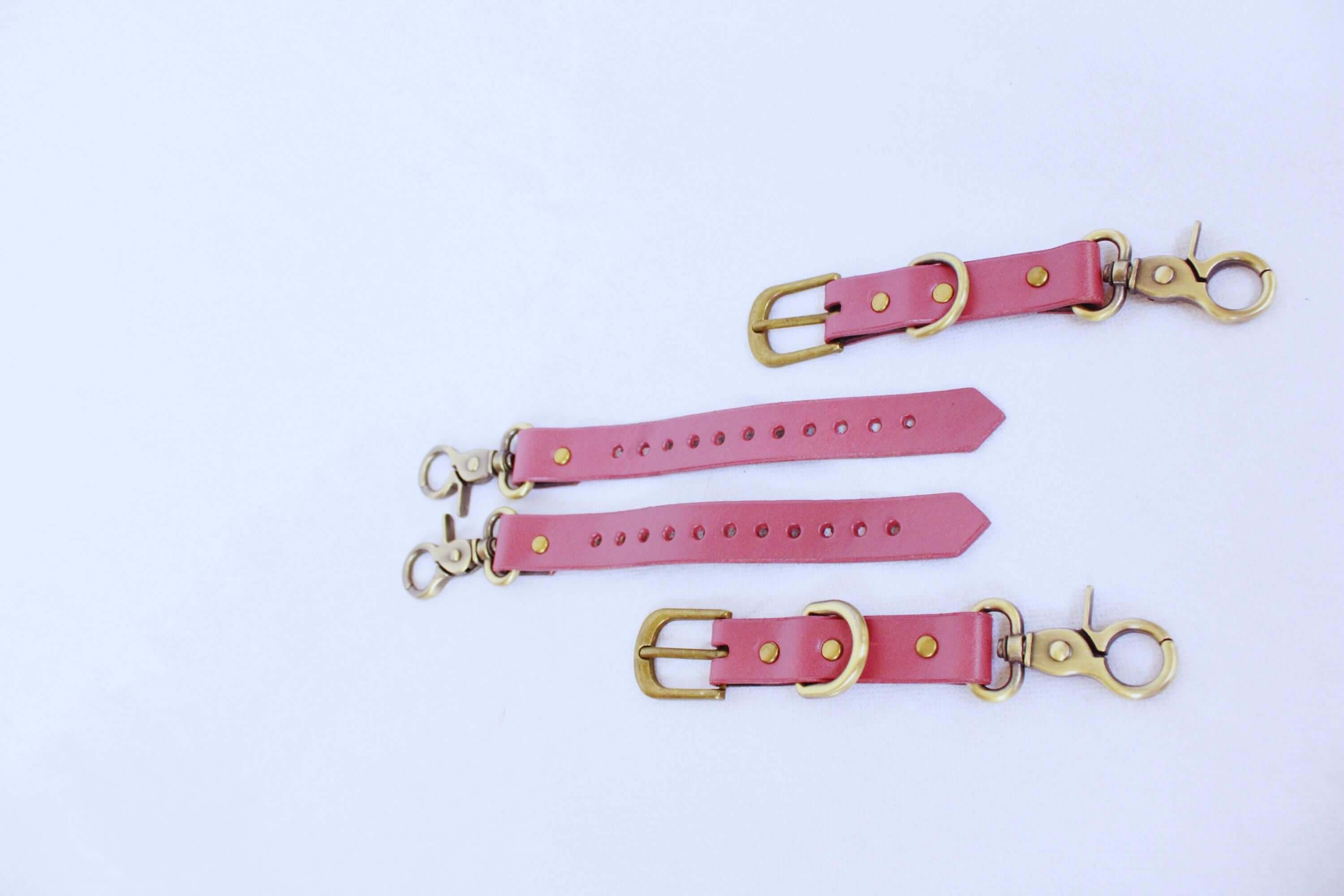 Adjustable BDSM Connector – Handmade leather restraint strap with brass hardware in pink.