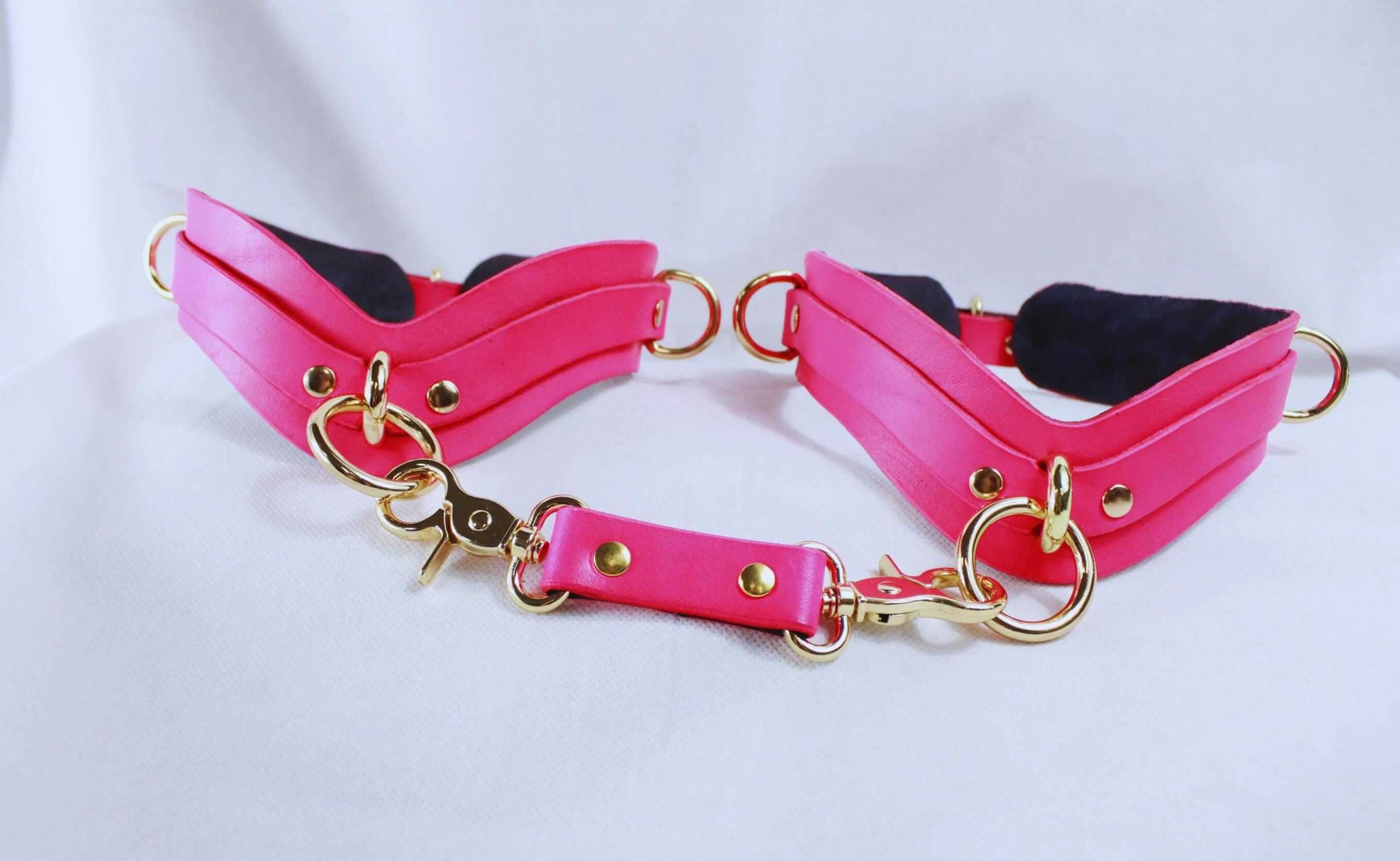Pink thigh cuffs with gold-tone hardware, perfect for BDSM and bondage adventures.