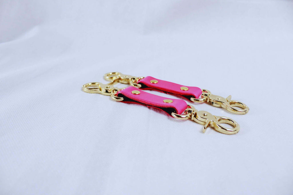 BDSM bondage connectors in hot pink with gold hardware, perfect for cuffs, collars, and harness play.