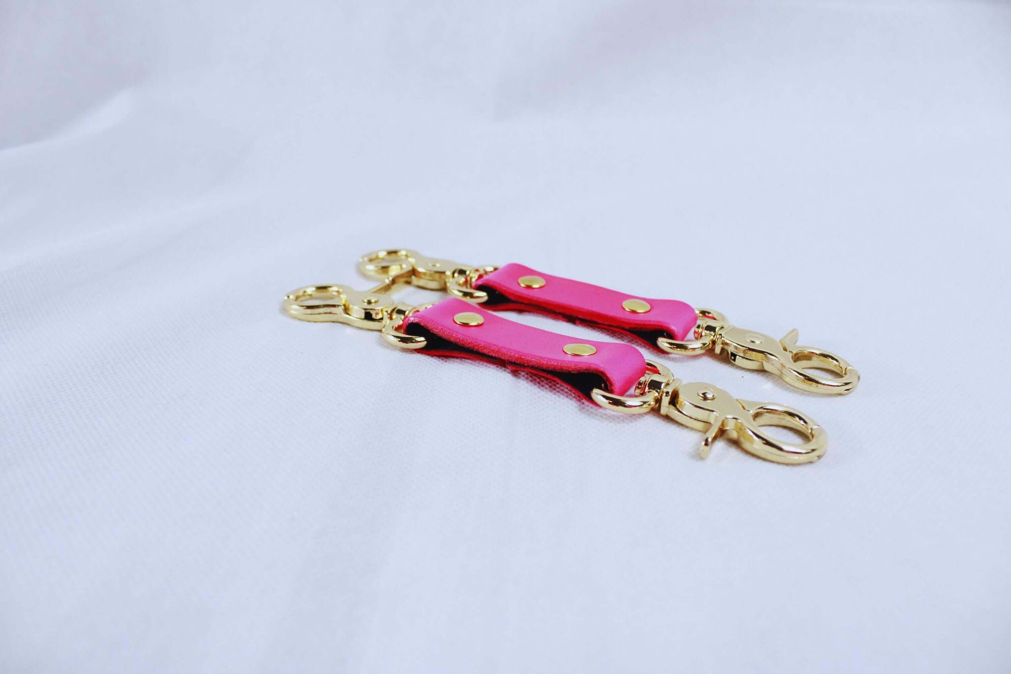 BDSM bondage connectors in hot pink with gold hardware, perfect for cuffs, collars, and harness play.