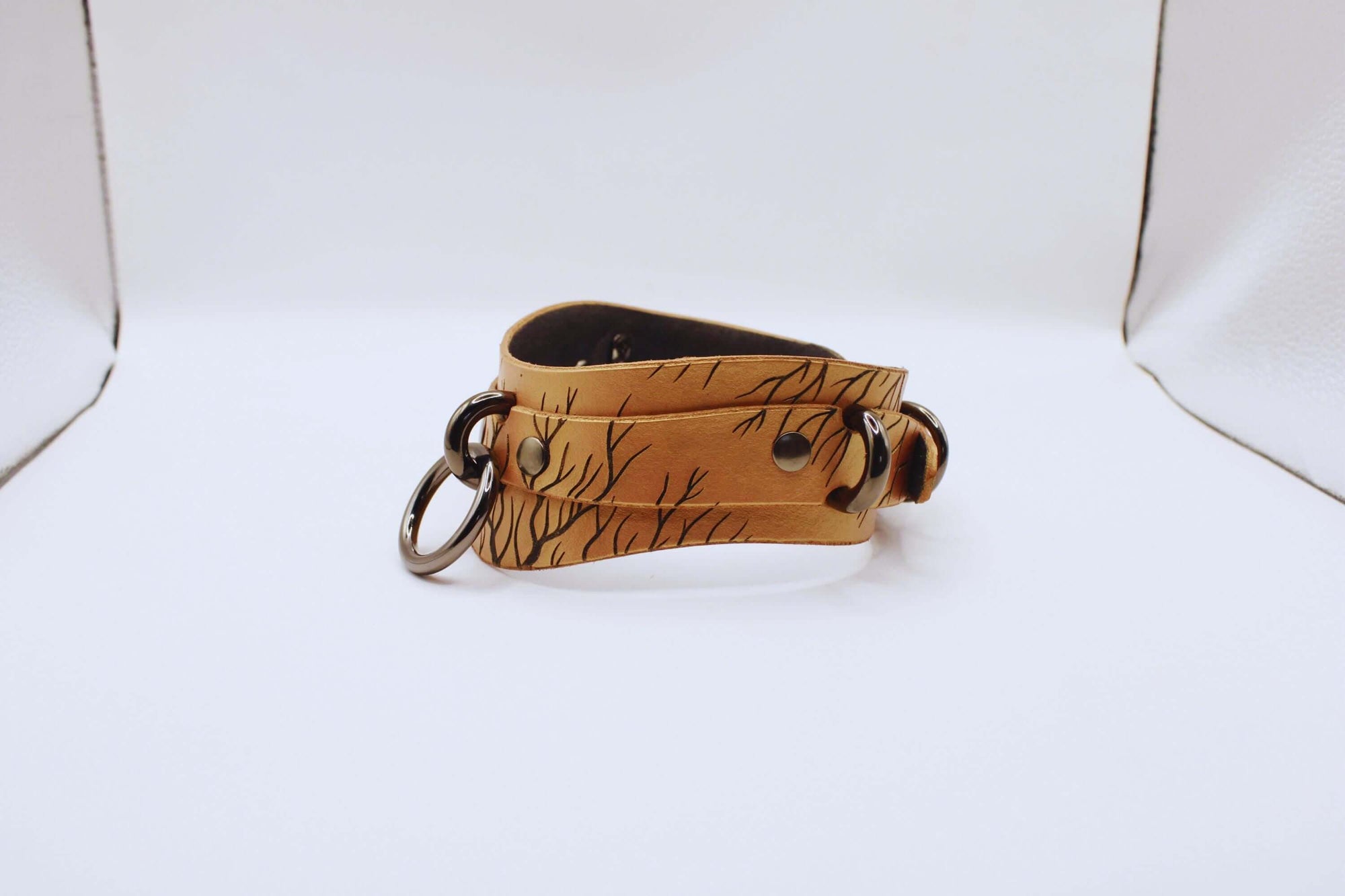 Elegant leather submissive collar featuring intricate nature-inspired patterns, perfect for a discreet BDSM accessory.