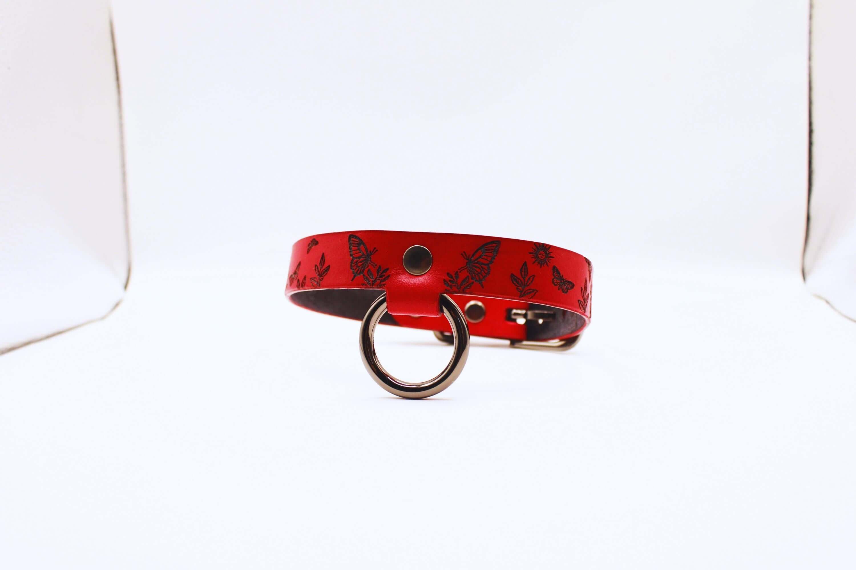 Deep red leather submissive collar with butterfly designs, perfect for BDSM enthusiasts.