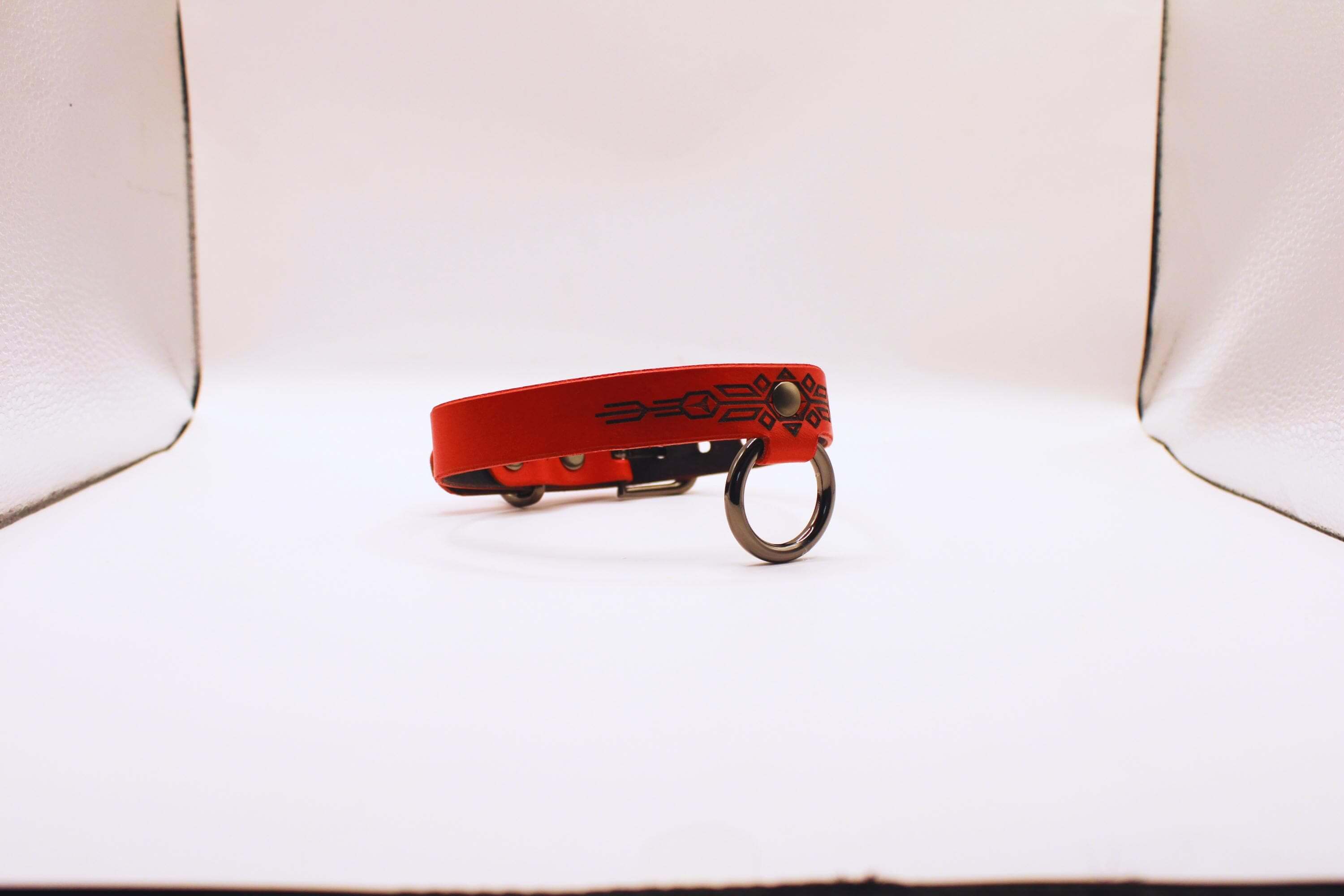Handmade submissive collar of fire, a discreet BDSM collar in red leather with geometric patterns.