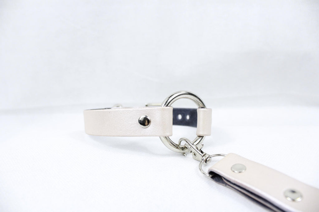 Close-up of a pearl silver leather BDSM collar with metal ring and clasp, ideal for submissive daywear and discreet styling.