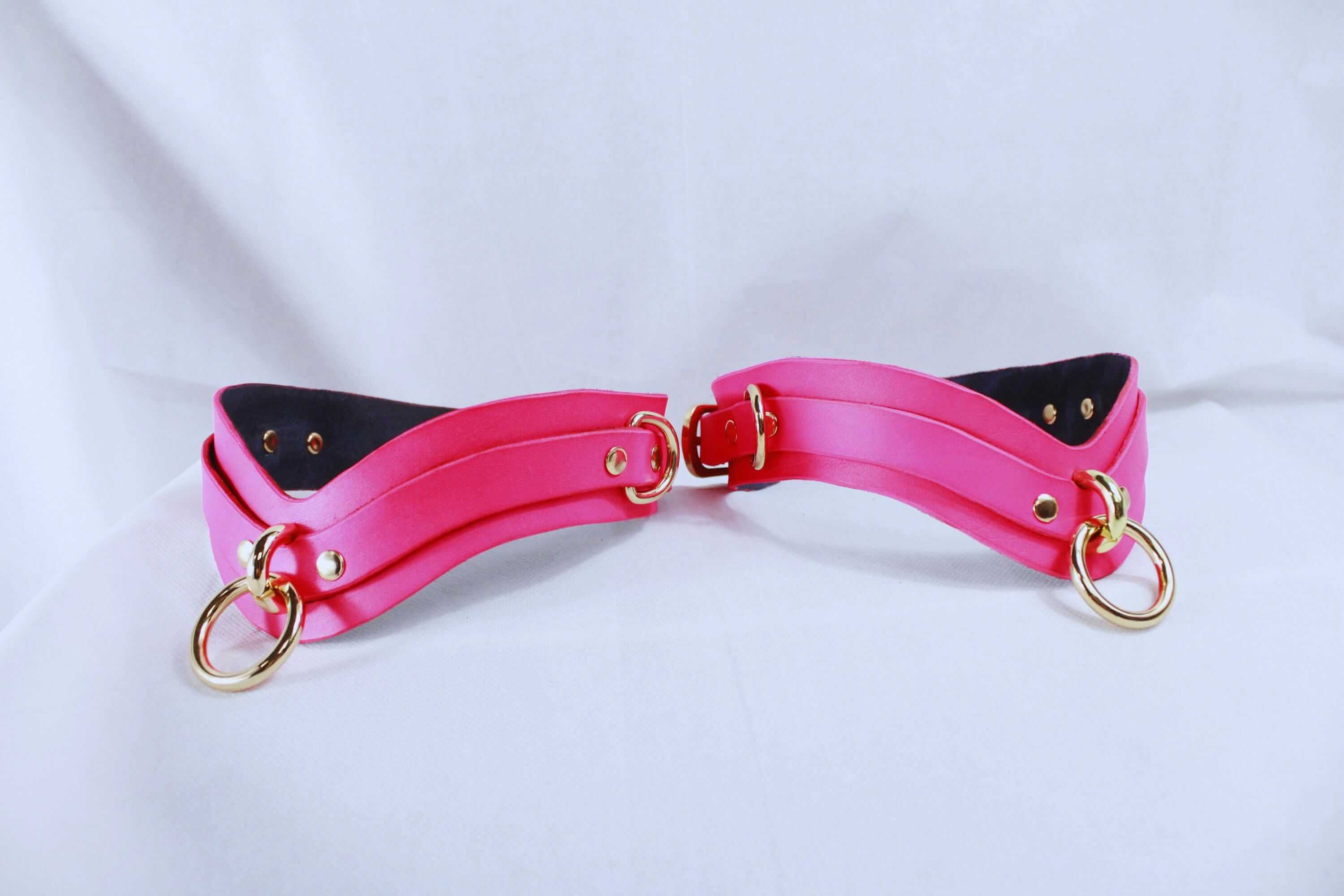 Pink thigh cuffs with gold-tone hardware, ideal for BDSM and bondage play, perfect for submissive and couples' adventures.