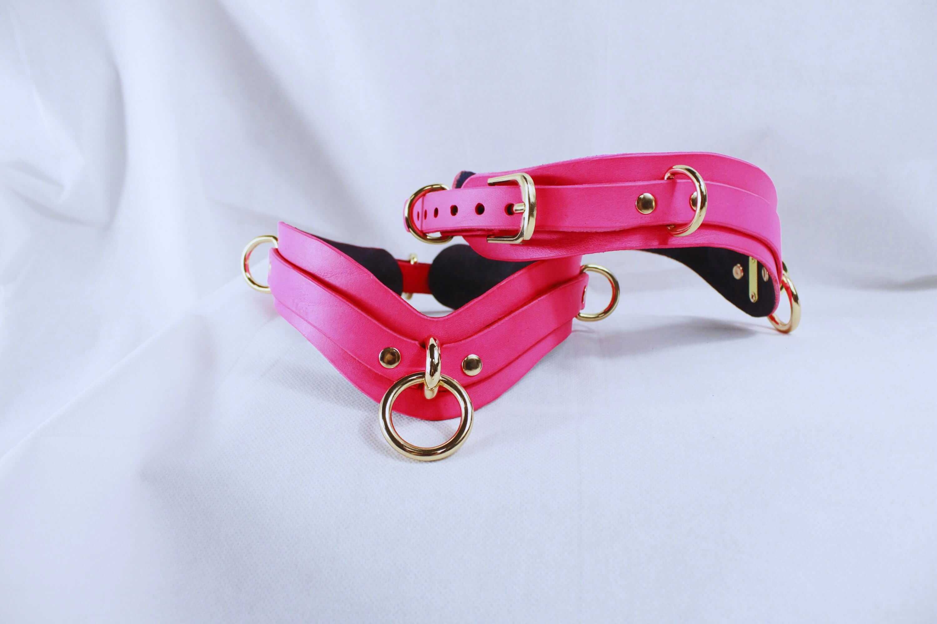 Pink thigh cuffs with gold-tone hardware, perfect for BDSM play and bondage gear, featuring a stylish design for couples.
